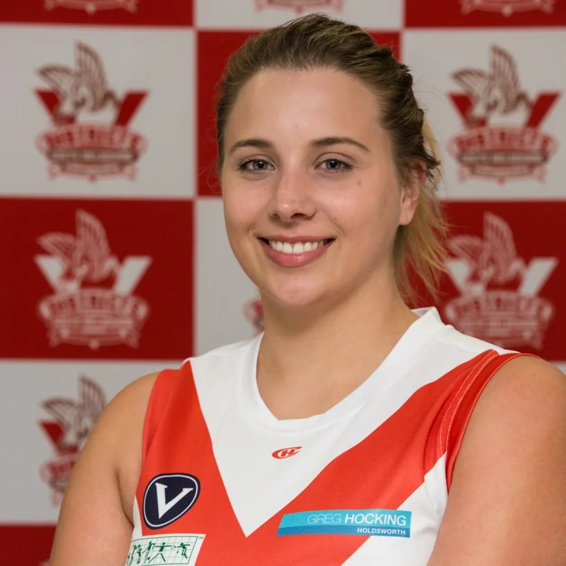 Jane This year our #4 player, and the reserves team captain, is Jane. She came to play football back in 2017 and joined the Bloods through the SMDFC skills academy. Jane has become a regular feature in our forward line. Jane has 2 big sporting achievements in her life- one is 1st place in C grade touch rugby and the other is for 1st place in a nacho eating competition- she couldn’t pick the best! Away from sport Jane is the proud mother of 19 houseplants who she takes great pride in and her dream is to be able to learn pottery to make all of them new pots to live in!