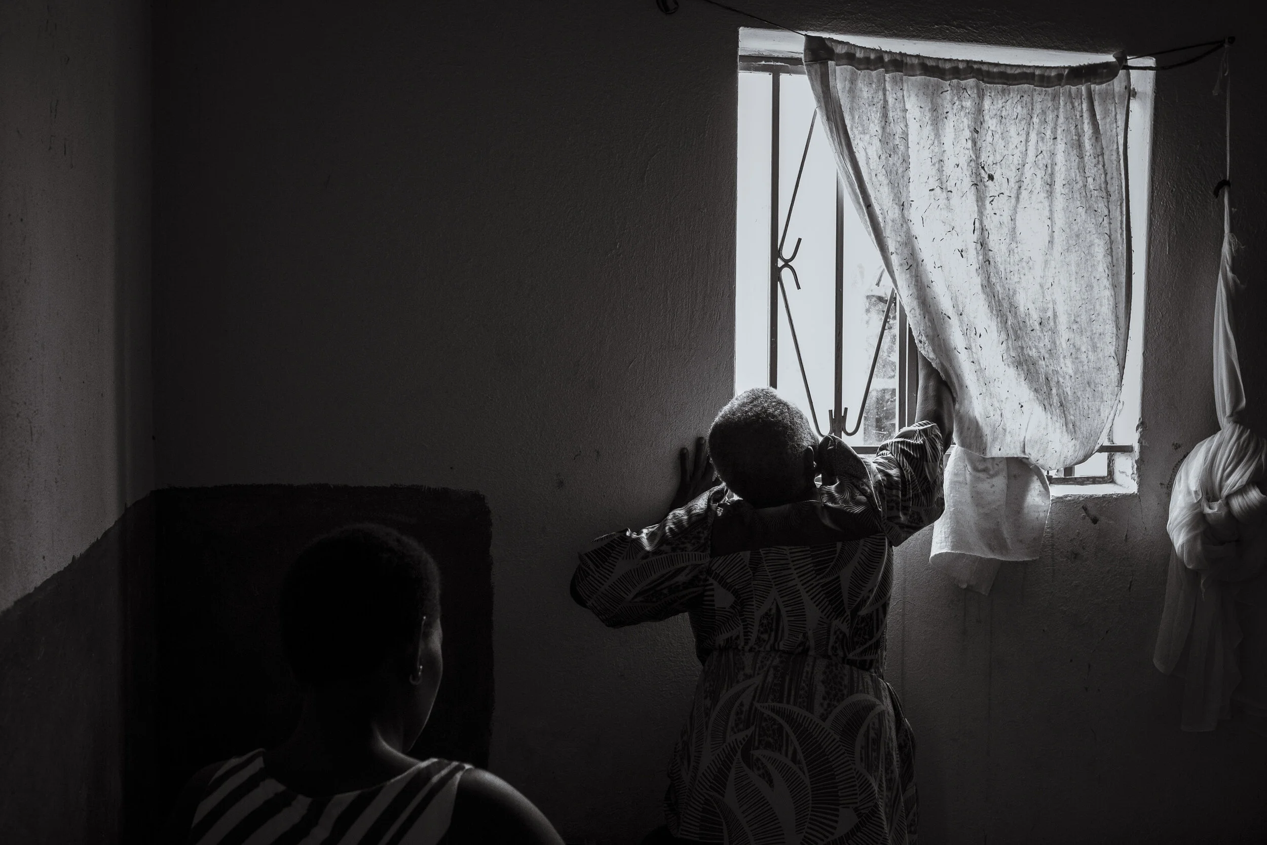  Kabaale, Entebbe. Ruth Nakimera closes the blinds for privacy before performing a routine check up on 25 year old Haddijjah Nabweteme, 8 months pregnant with her fourth child. Nakimera  is a traditional birth attendant. Not medically trained, tradit
