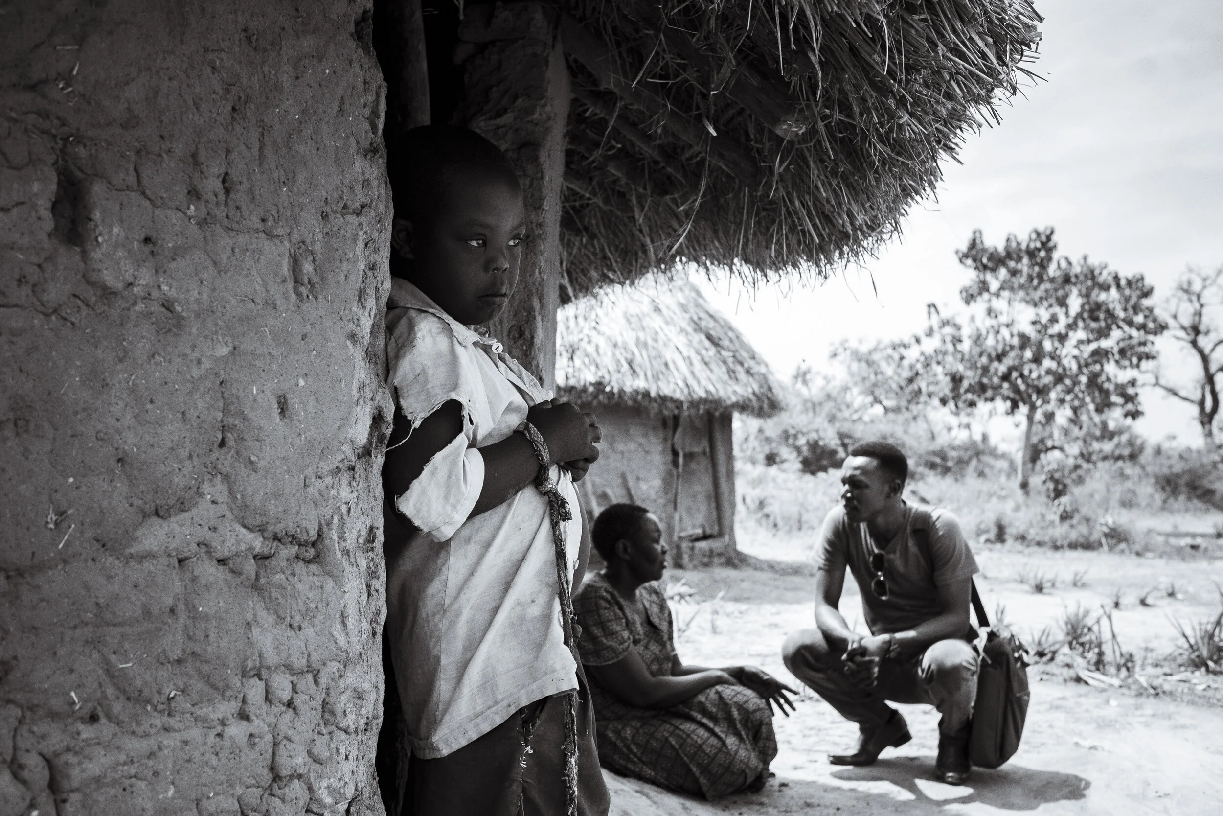  Obur, Uganda. Pastor Fred Alimet, who works as a community outreach worker to bring awareness to rural areas about the taboos surrounding disability, speaks to Elizabeth Ilolu, the mother of 13-year old Silus Odii who is seen with the rope that is u