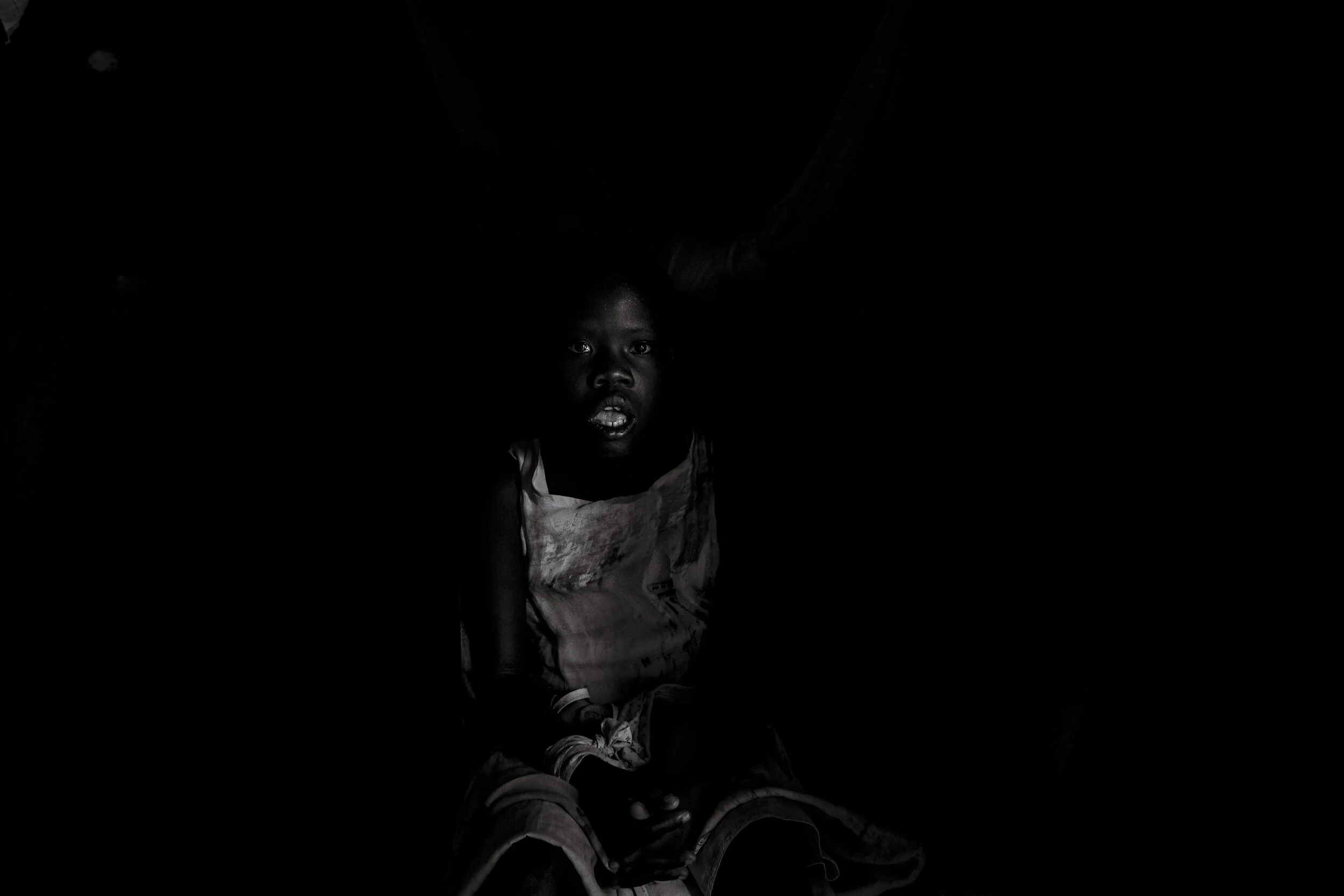  Obur, Soroti District. Twelve year old Catherine Asinge is bound by her right wrist to a chair   in a village storehouse with some chickens and sacks of Casava. She looked bewildered by the light as the storehouse door was opened. Un-diagnosed and s