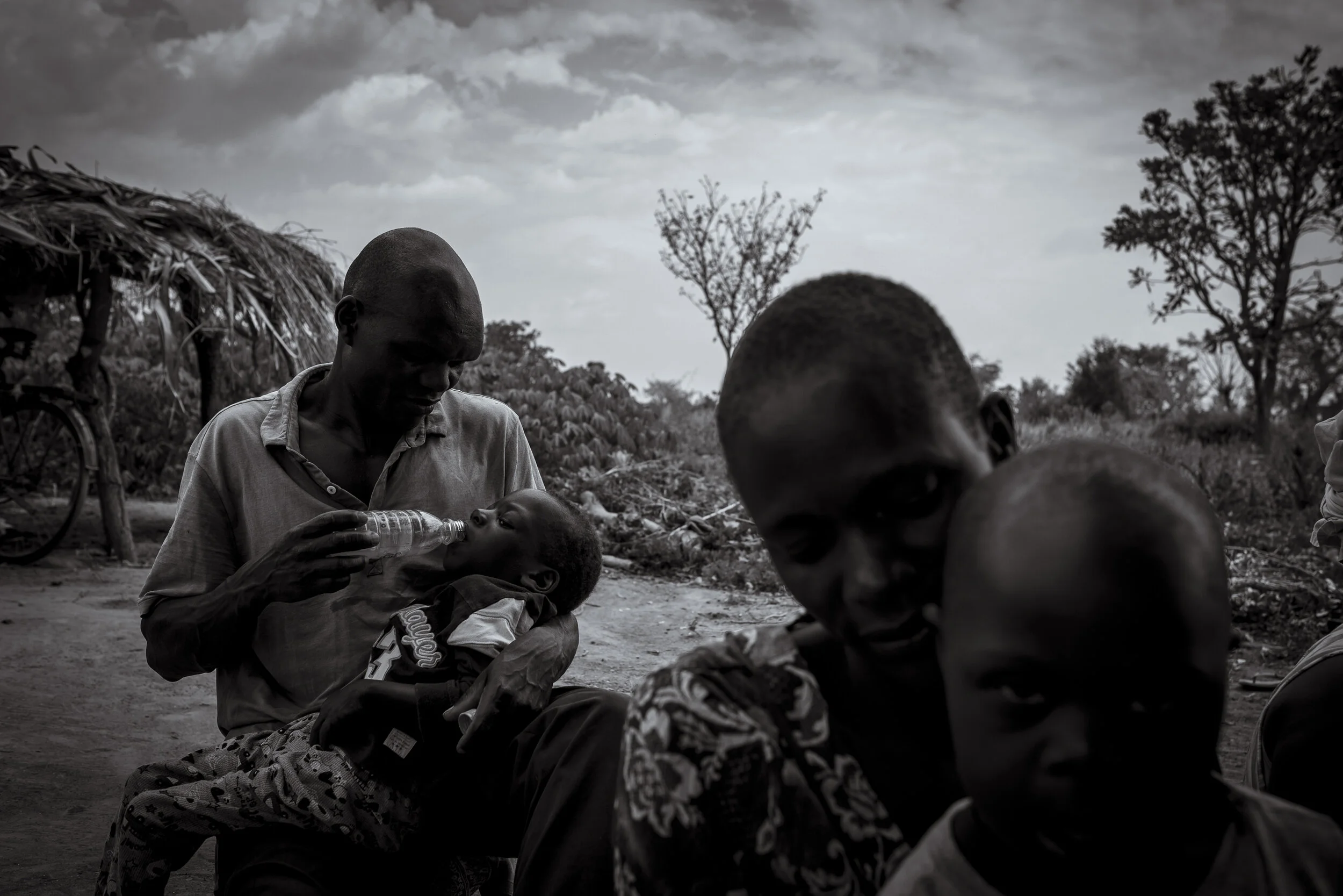  Obur, Soroti District. Simon Okurut has travelled with his son Paul to a community outreach information session hosted by Pastor Fred Alimet. Simon cares for Paul alone after his wife fled their village after Paul's diagnoses.  Simon is a minority i