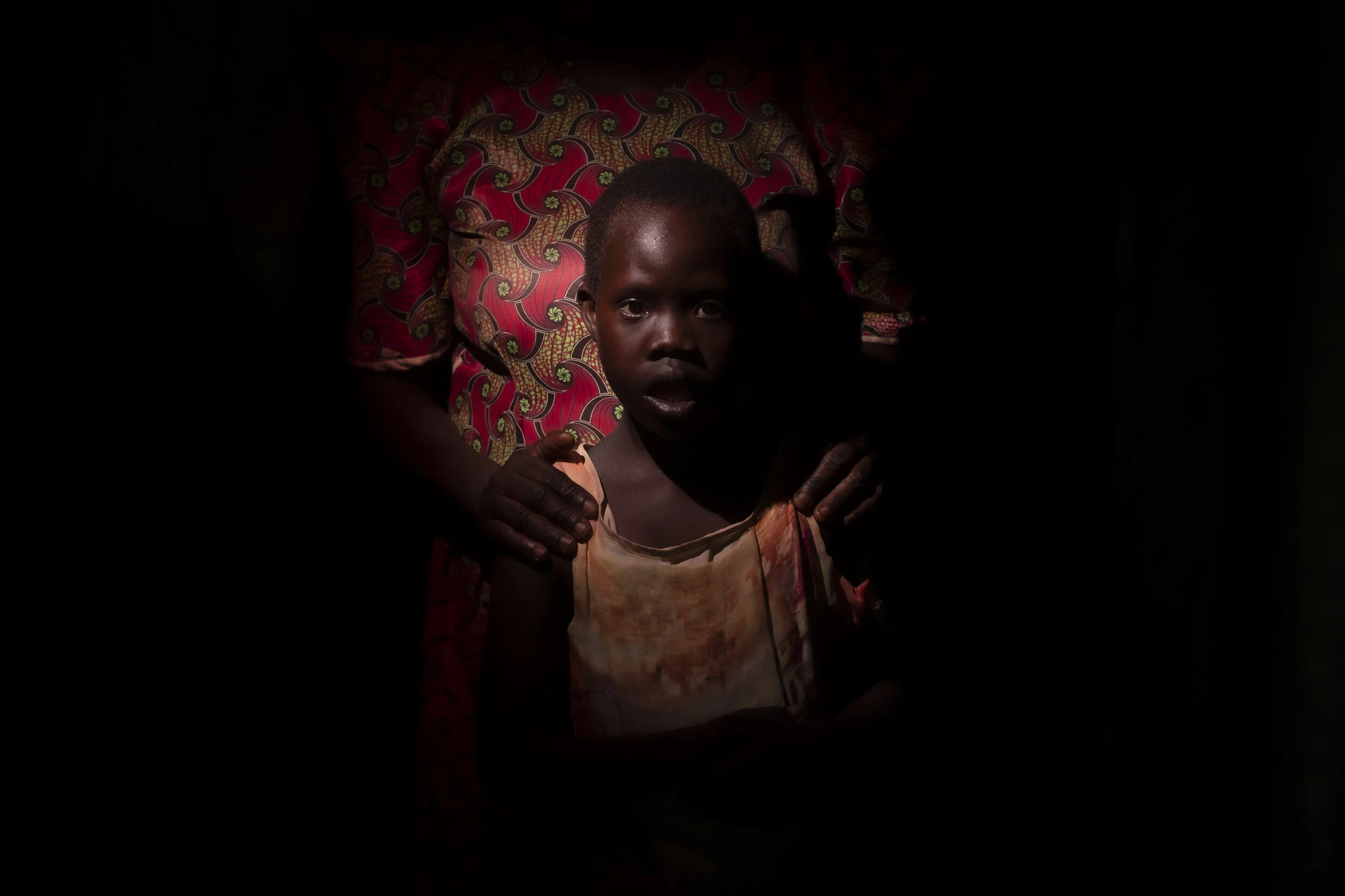  Obur, Soroti District. Twelve year old Catherine Asinge is bound daily to a chair in a storehouse with chickens and sacks of Cassava. She looked bewildered by the light as the storehouse door was opened. Un-diagnosed and speechless, she now resides 