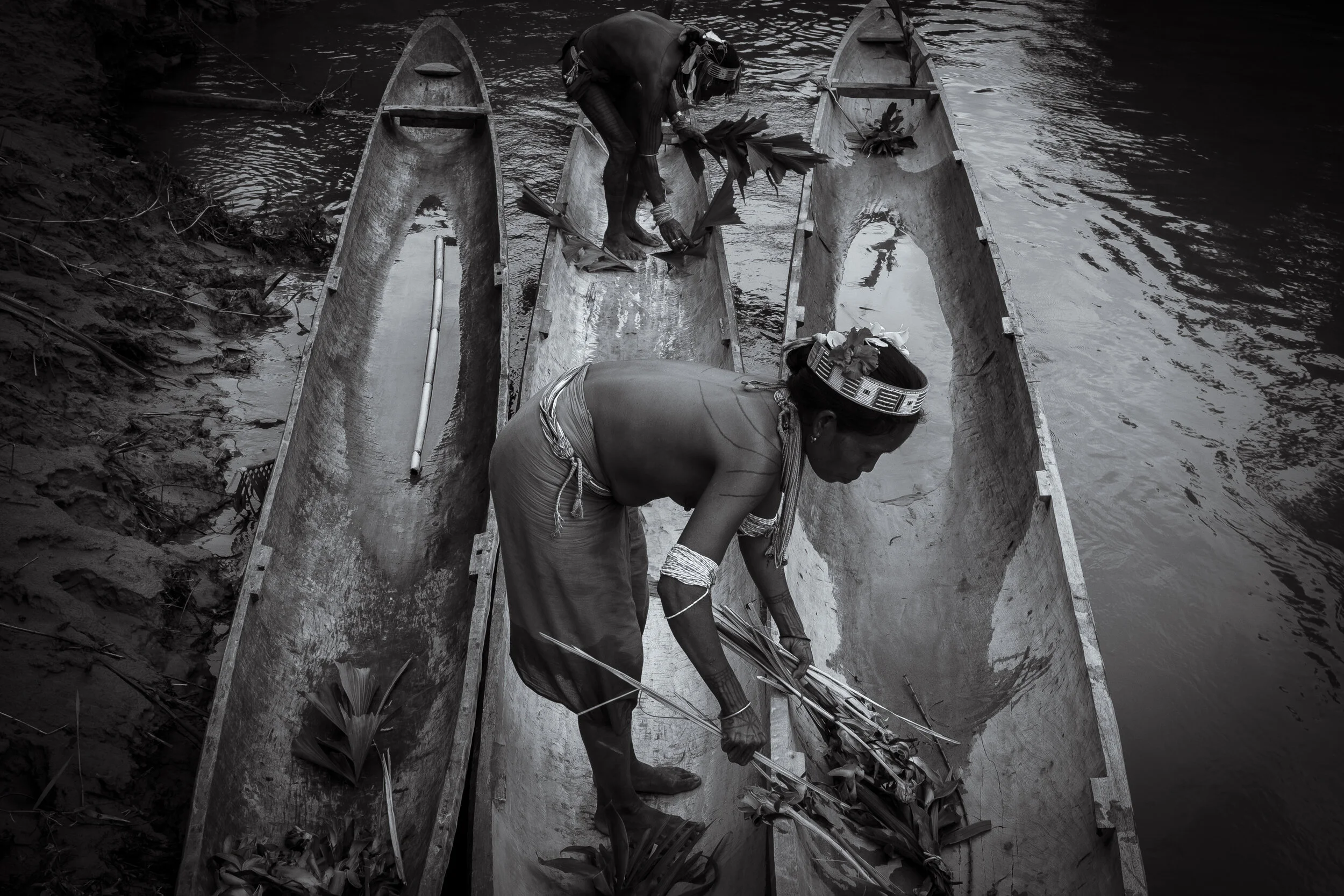  Masit Dere's wife Godai Manai blesses the new boat with the articles of the jungle collected by her husband a day earlier. The duty of the Sikerei wife is not only to tend to the children and the affairs of the home, but also to actively take part i