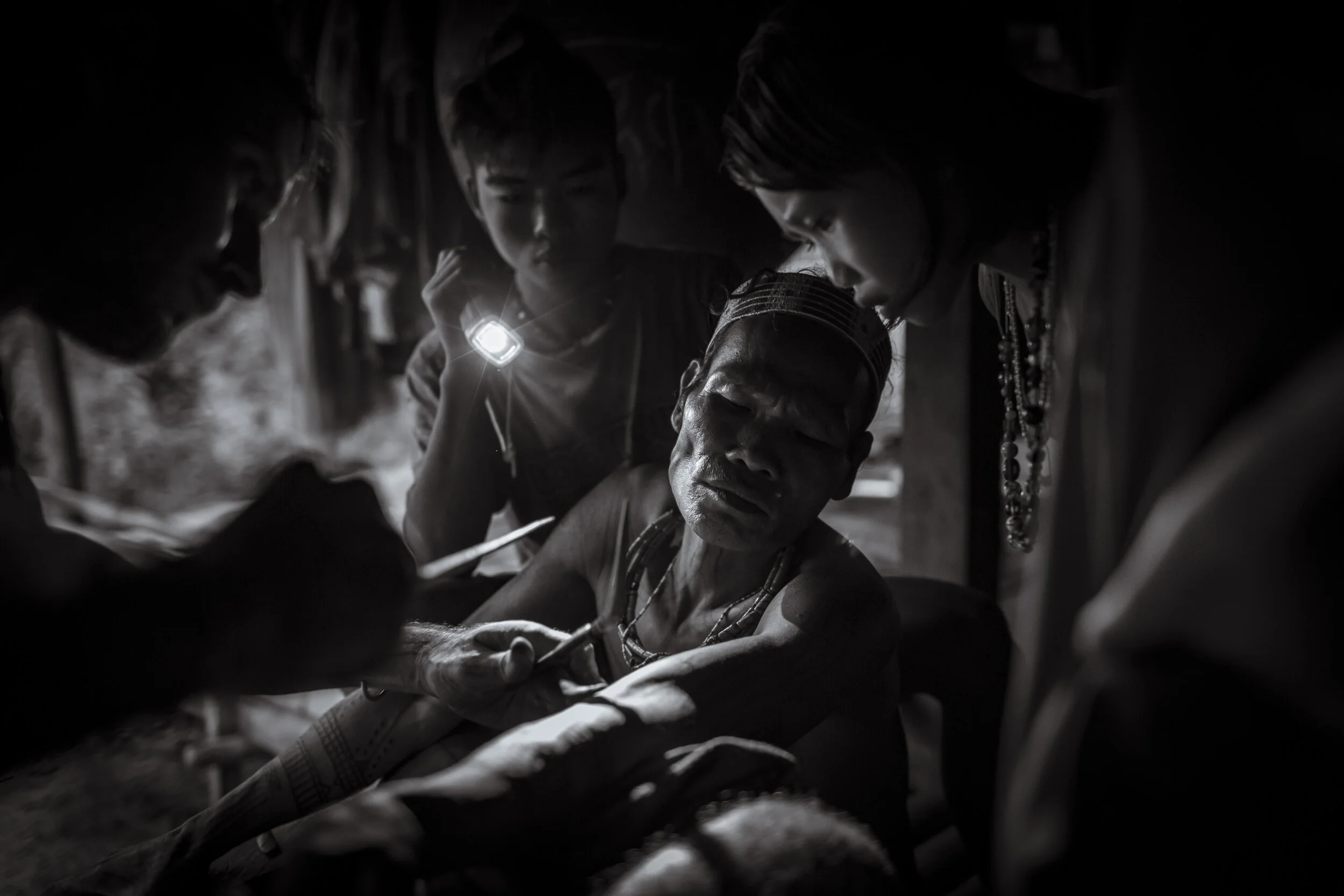  Aman Dussa Kunen is watched by local children as he is tattooed under torch light using the traditional Mentawai hand-tapping technique. A practise that is becoming less common as their culture fades, the identity shaping markings, or Titi, are worr