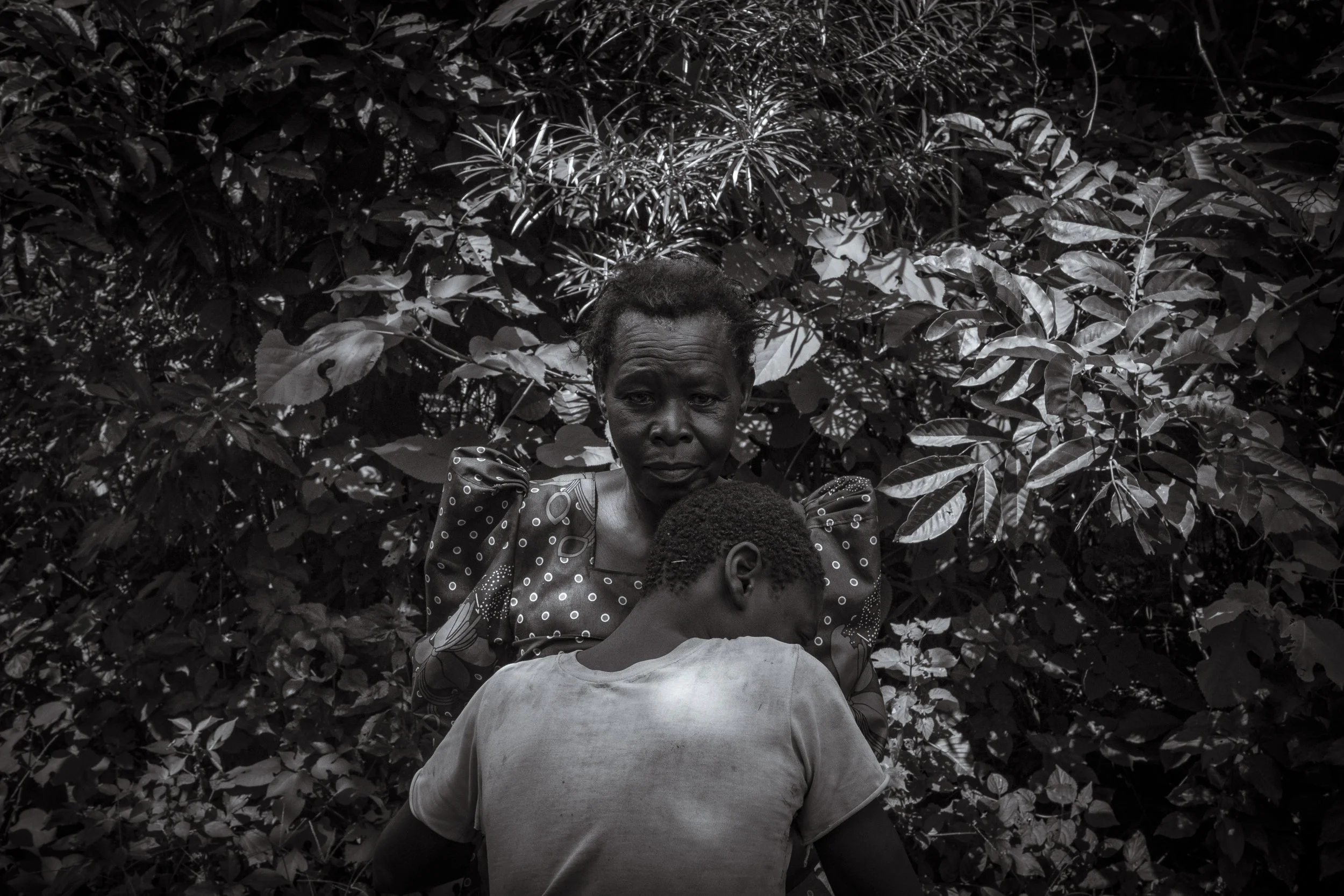  19 July 2023. Nabwigulu, Kamuli District, Uganda. Perez Mbwase cuddles into his mother Lovinsa Namwebya's bosom after being admonished for misbehaving.   Due to his Autism, hunger is a trigger for Perez' mood to swing towards aggression. After walki