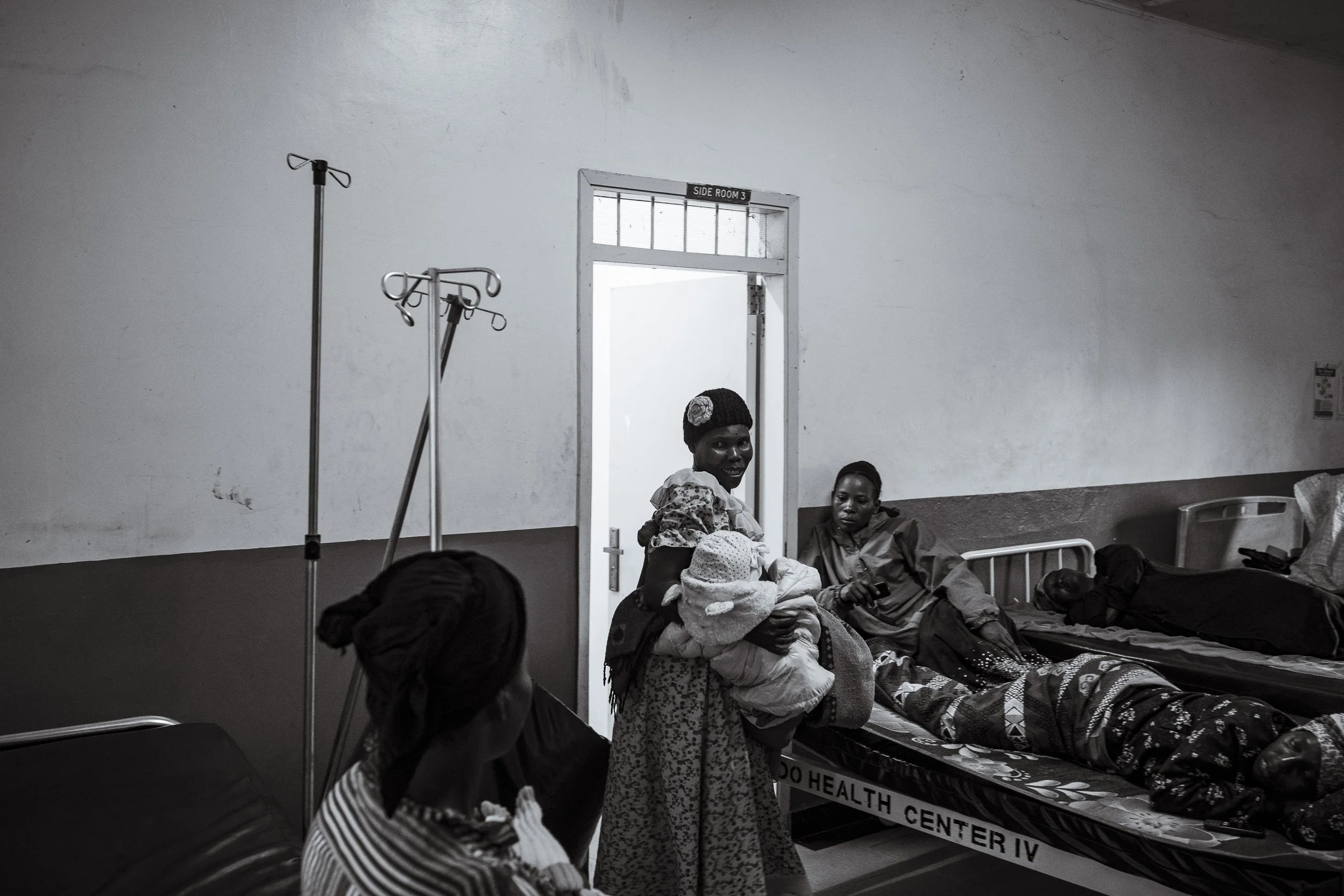  27 November 2024. Budondo, Uganda. At the Budondo Government Hospital, Margret Awebwe carries her one-year-old Elaija Talemwa, who lives with Cerebral Palsy from his monthly therapy session with physiotherapist Alex Kamulegeya. The lack of prioritis