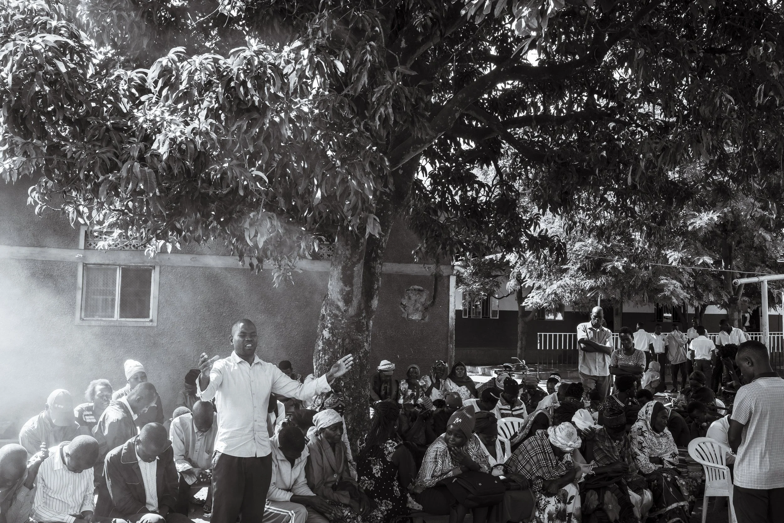  29 November 2024. Buwenge, Uganda.  A local participant in a community outreach program says a prayer for those living with epilepsy who have congregated under a Mango tree to receive education and medical supplies. This outreach program, run by Ste
