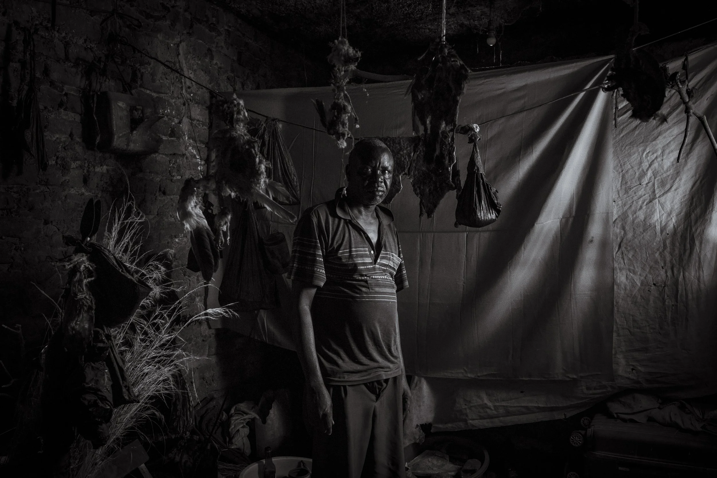  4 December 2024. Omalera, Soroti District, Uganda.  Local witch doctor Robert Apedu poses for a portrait in his clinic. As  witch doctors comprise around 77% of the health services in rural areas  they offer a more convenient alternative to the citi