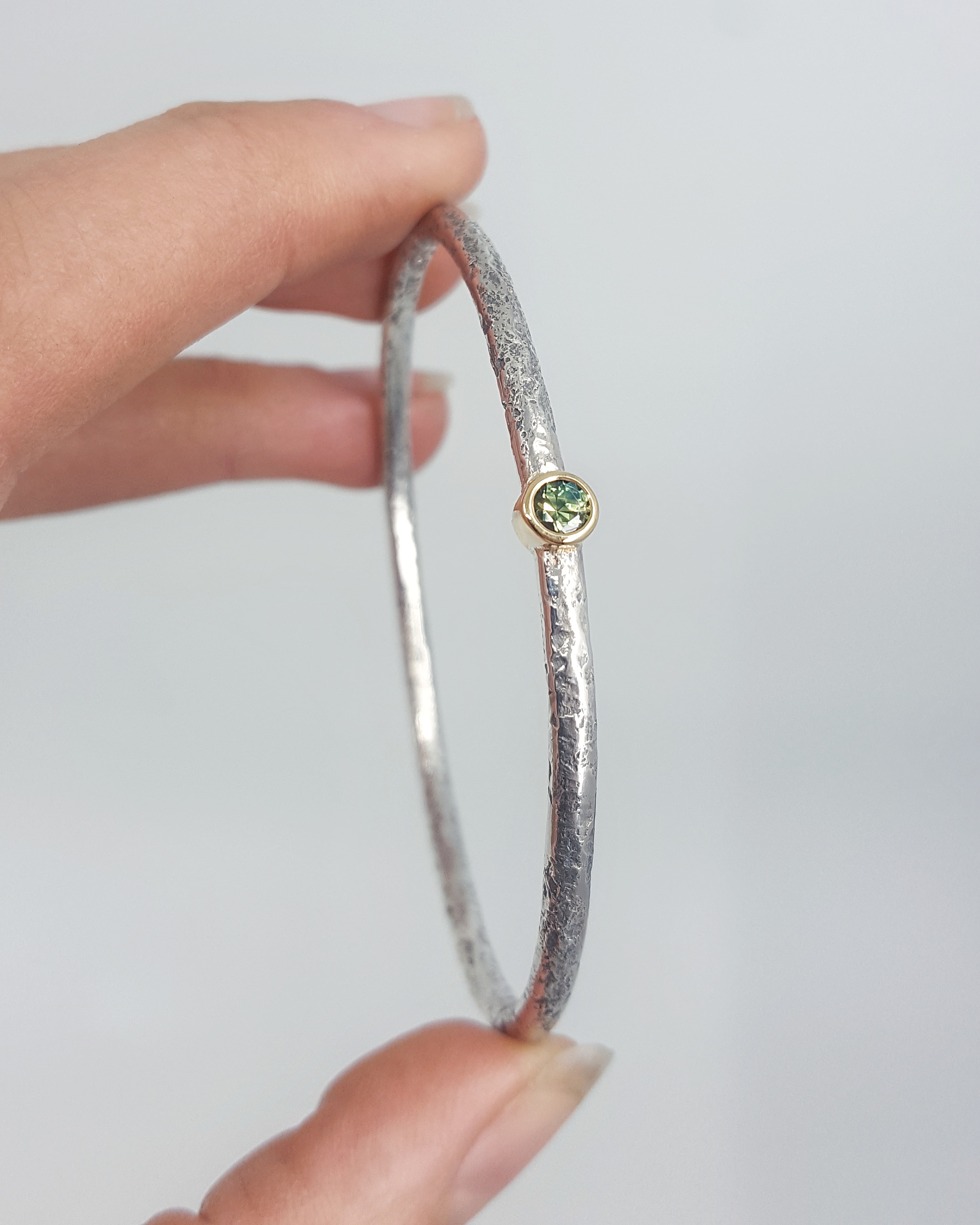Sterling silver textured bangle with 30pt Australian sapphire set in 18ct yellow gold bezel - $725