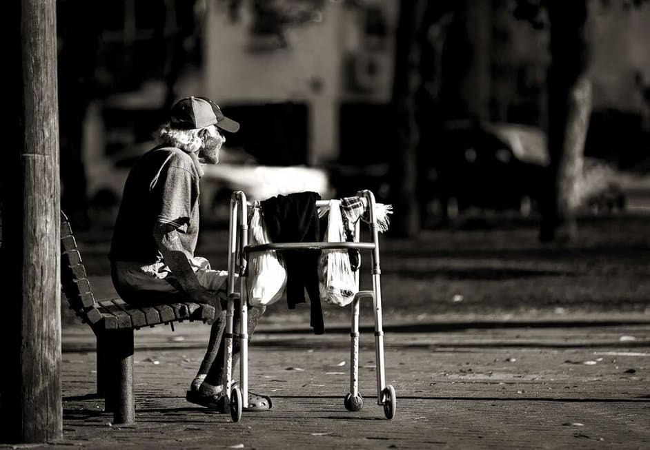 צילום רחוב שבו מופיע אדם מבוגר על ספסל