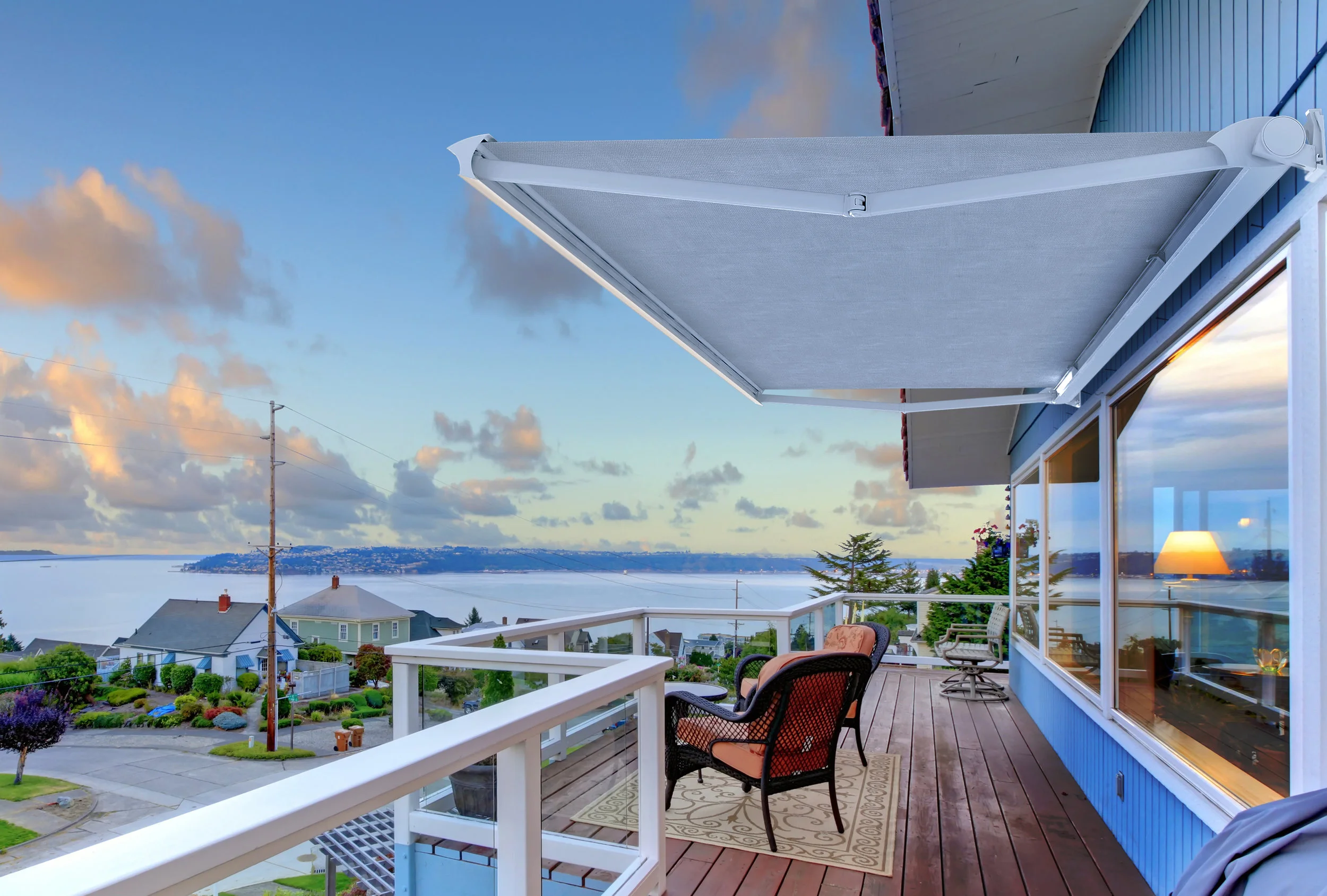 Large balcony of blue house with chairs and water view.