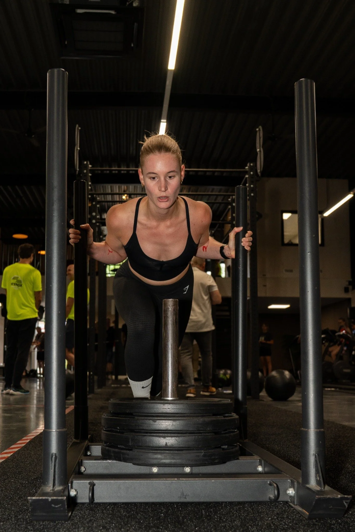 Vrouw die een farmschop met een gewicht optilt in een sportschool.