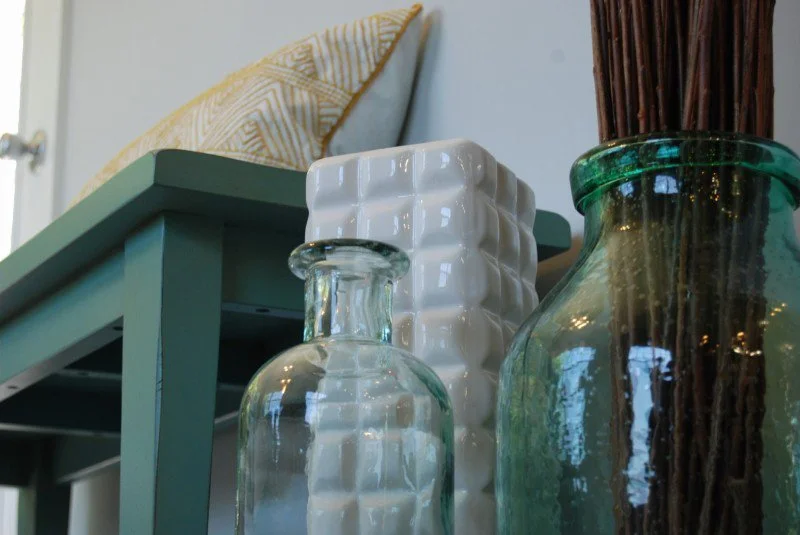 Close-up of decorative vases and a cushion on a table or shelf.