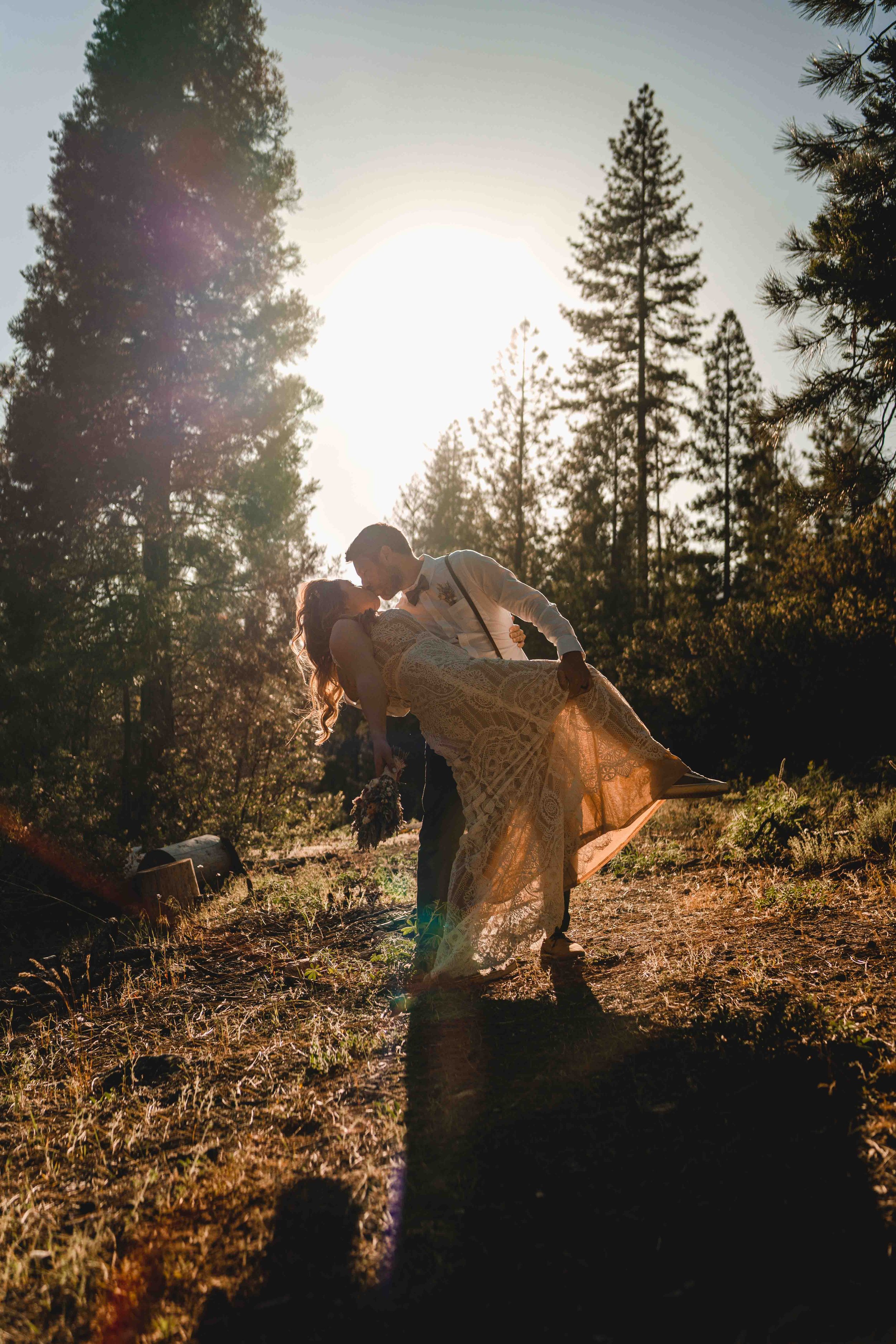 Groom dipping bride and kissing during sunset in the forest