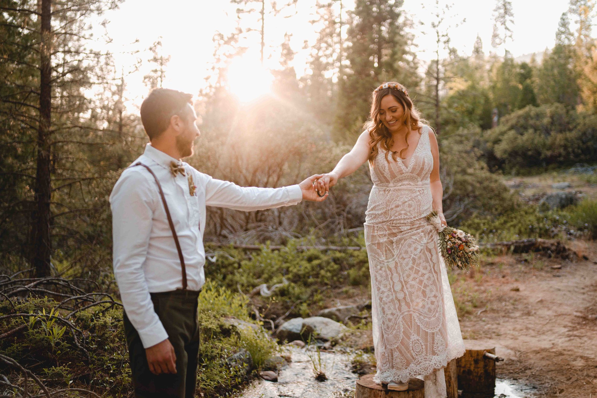 Groom helping the bride cross a stream