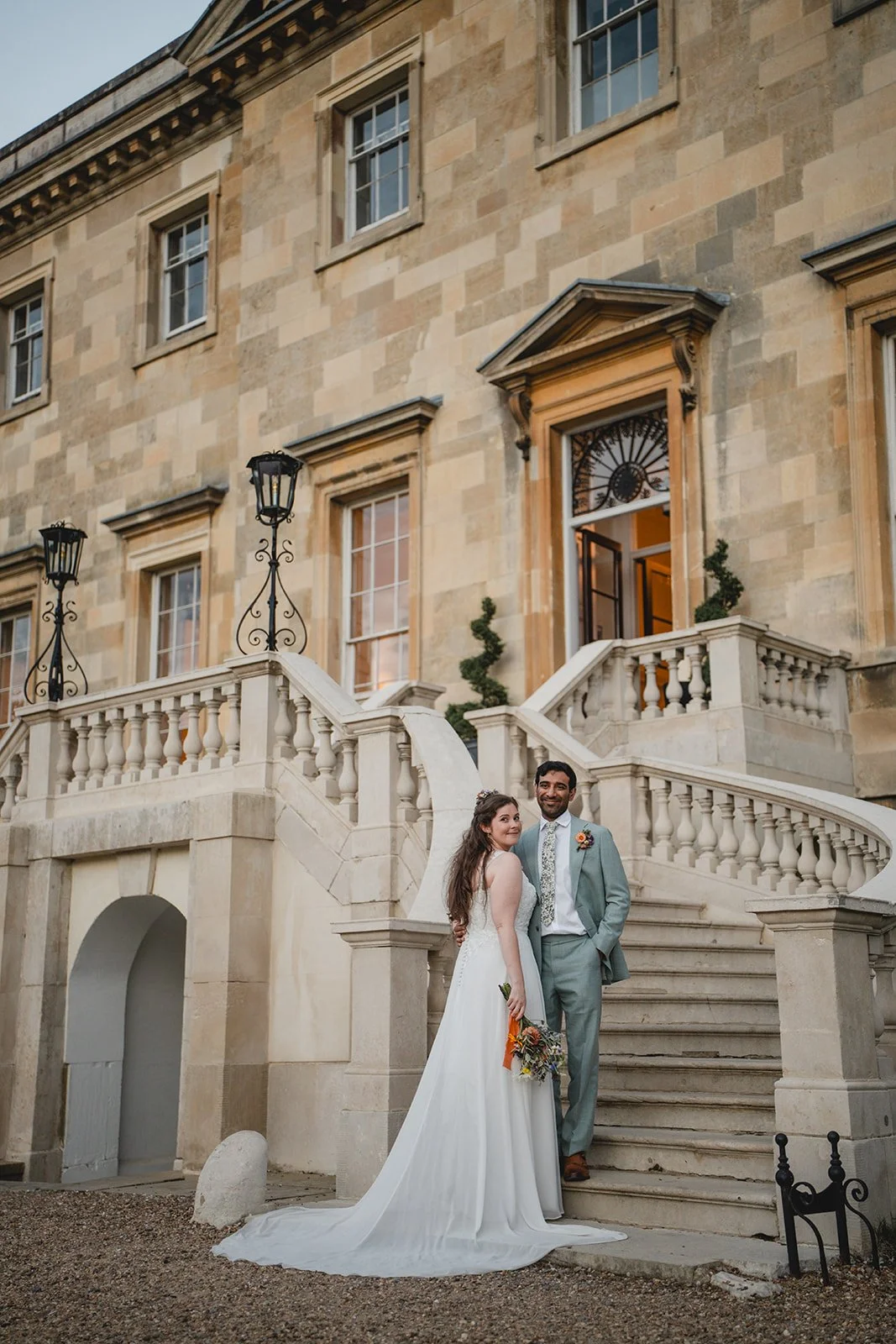 Dorothea and Peter standing on staircase outside country house