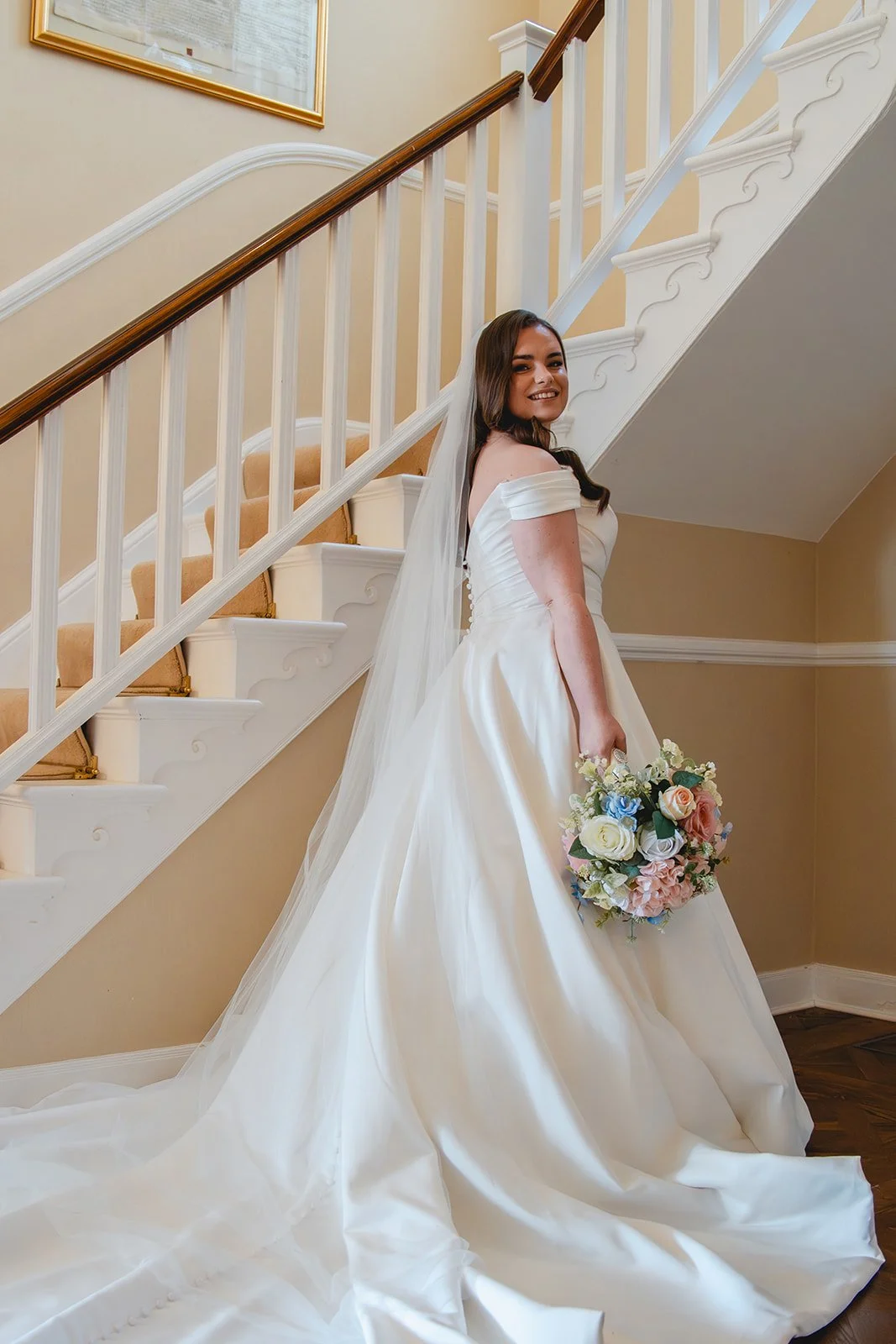 Shannon smiling in her wedding dress on the staircase