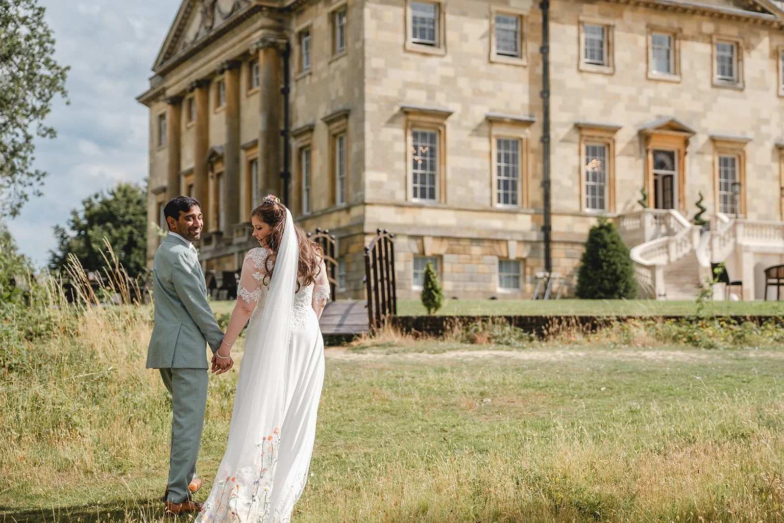 Dorothea and Peter holding hands outside country house venue