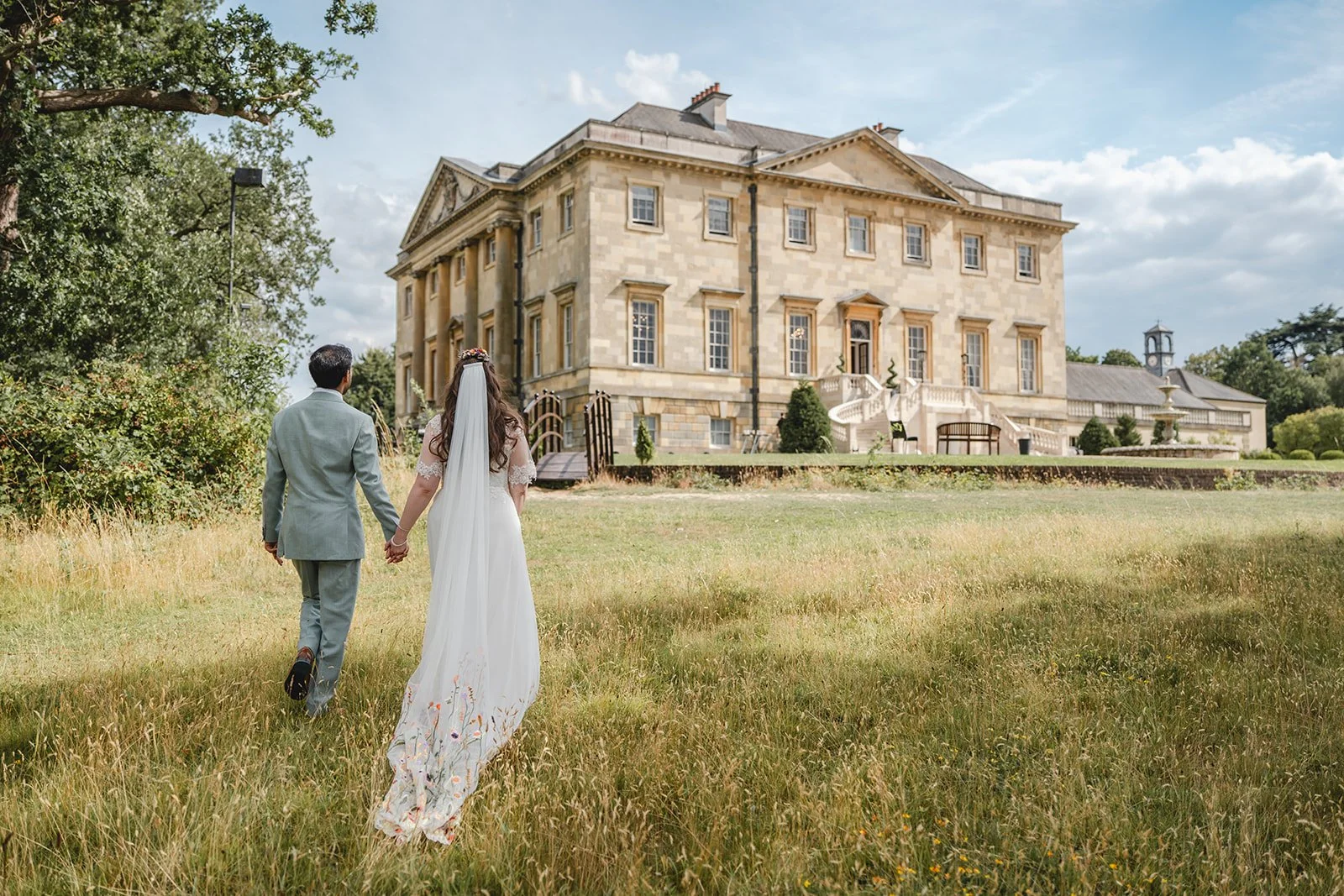 Dorothea and Peter holding hands in meadow outside venue