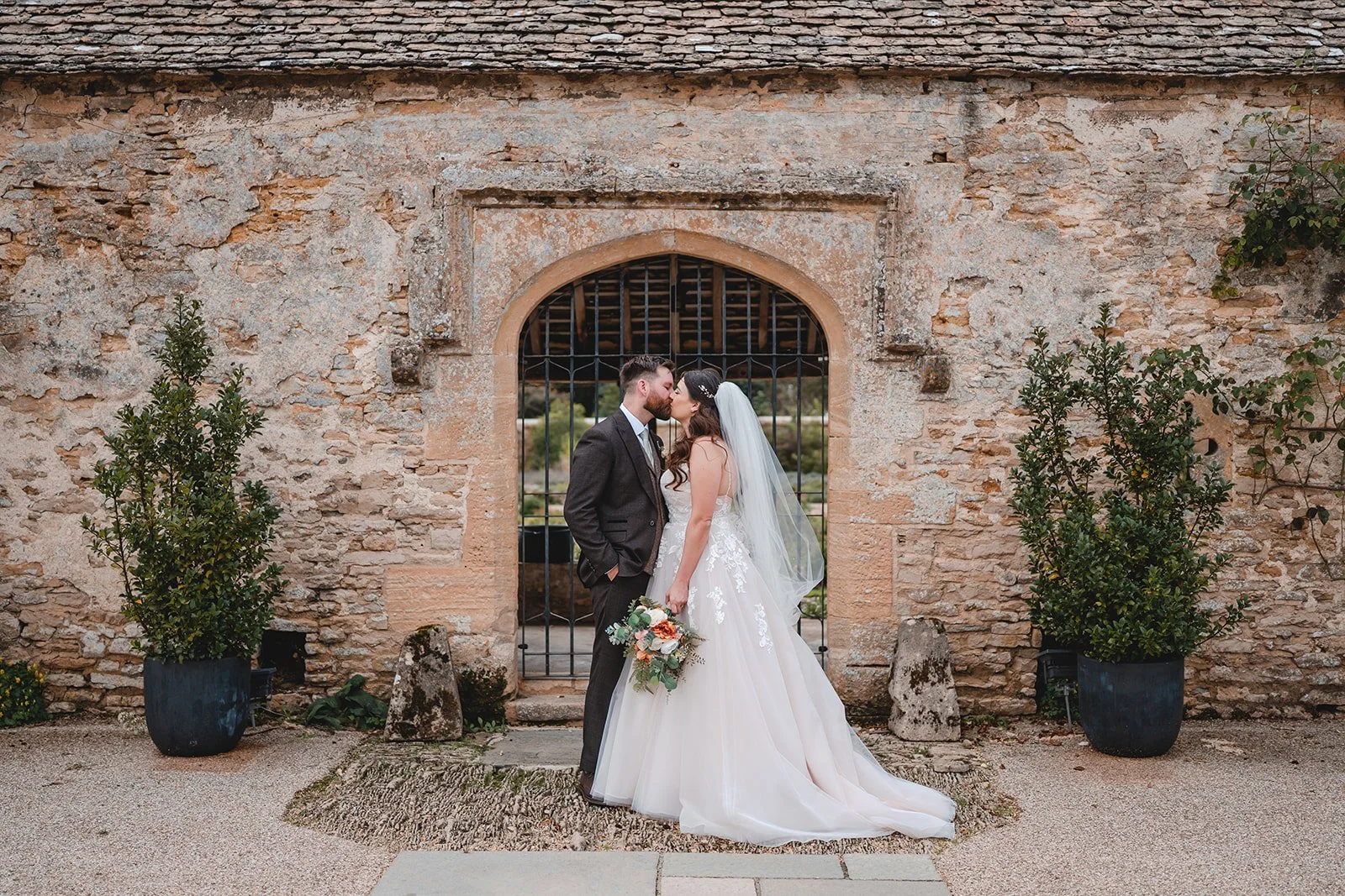 Sartis and Callum kissing outside stone wedding venue