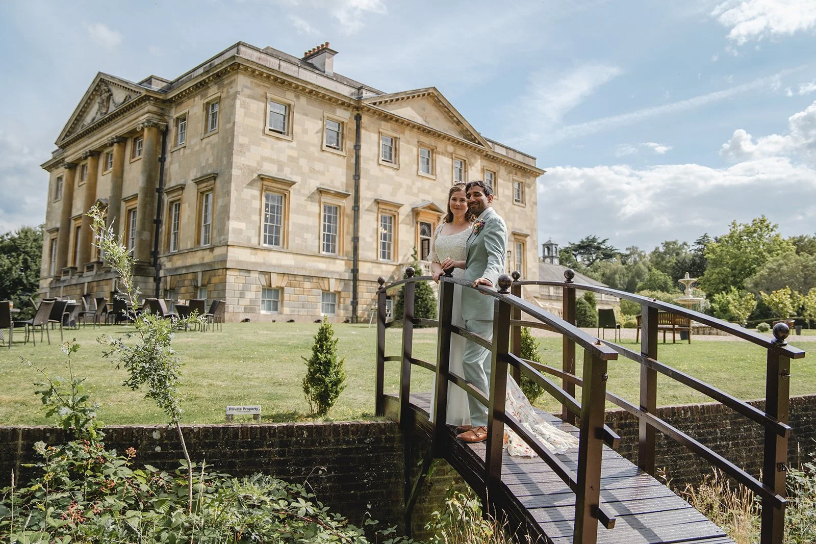 Dorothea and Peter standing on bridge outside country house wedding venue