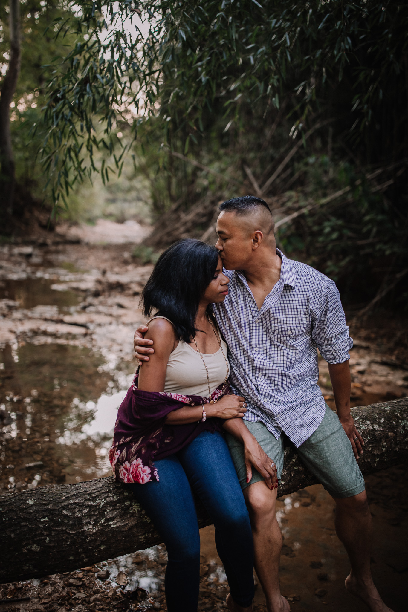 man and woman sitting on tree kissing