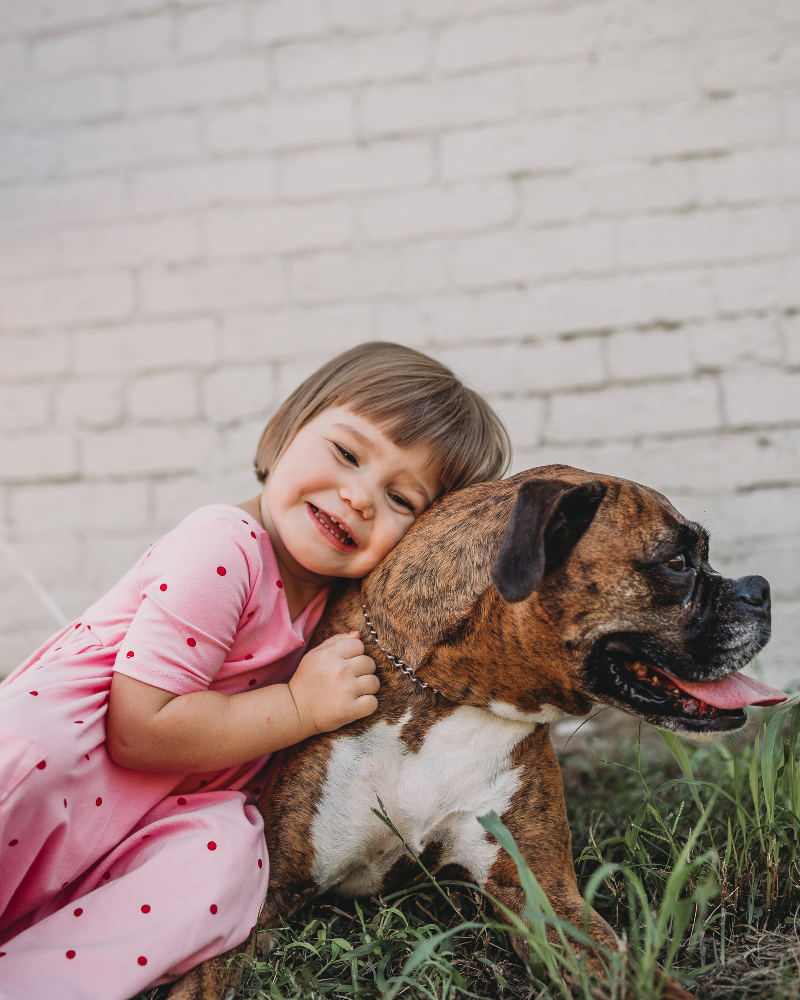 little girl hugging boxer dog