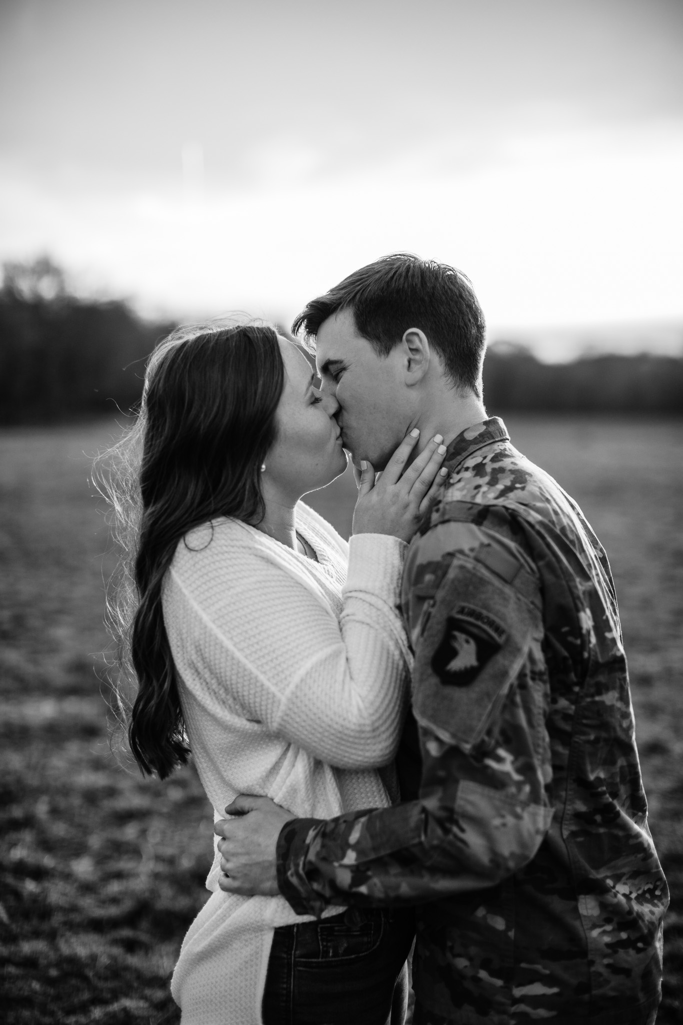 black and white photo of couple kissing with man in uniform