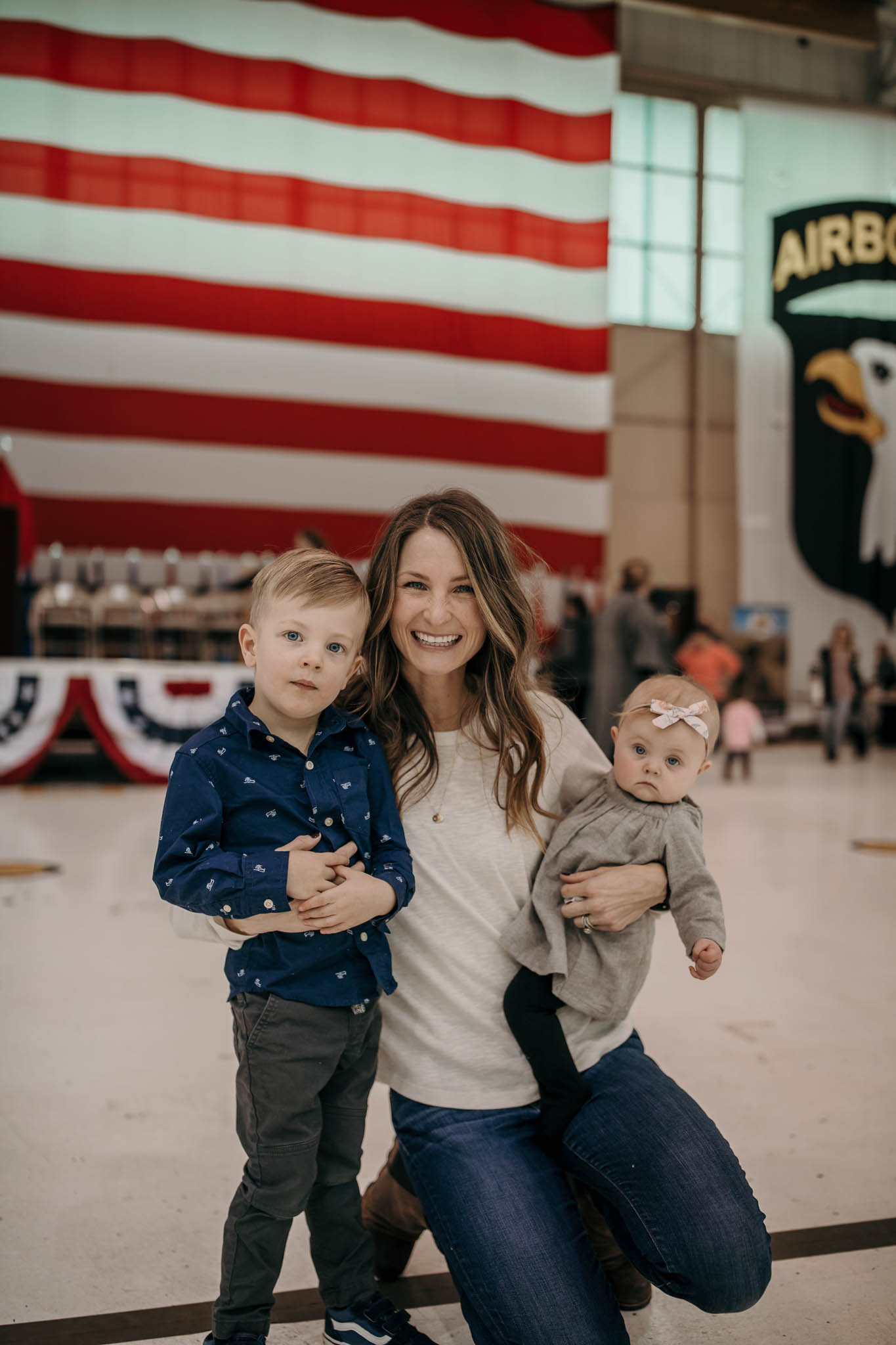 Army Wife Standing with Children infron of Flag