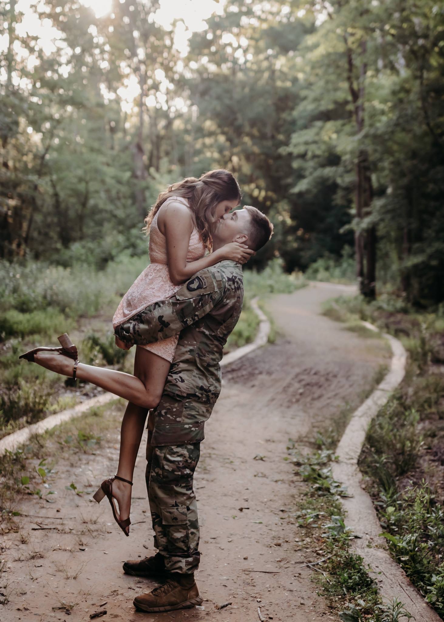 Soldier holding his girl as they kiss on a pathway 