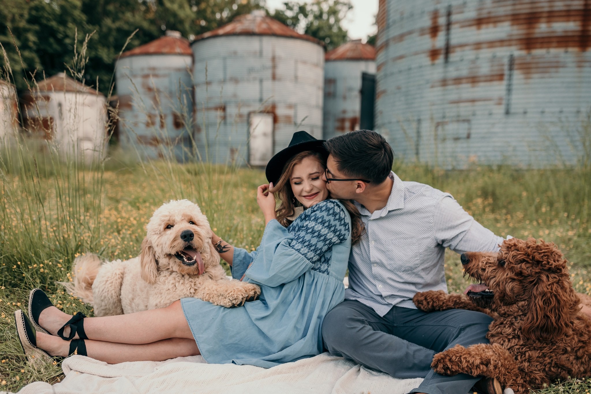 Couple sitting on a blanket together with their two goldendoodles