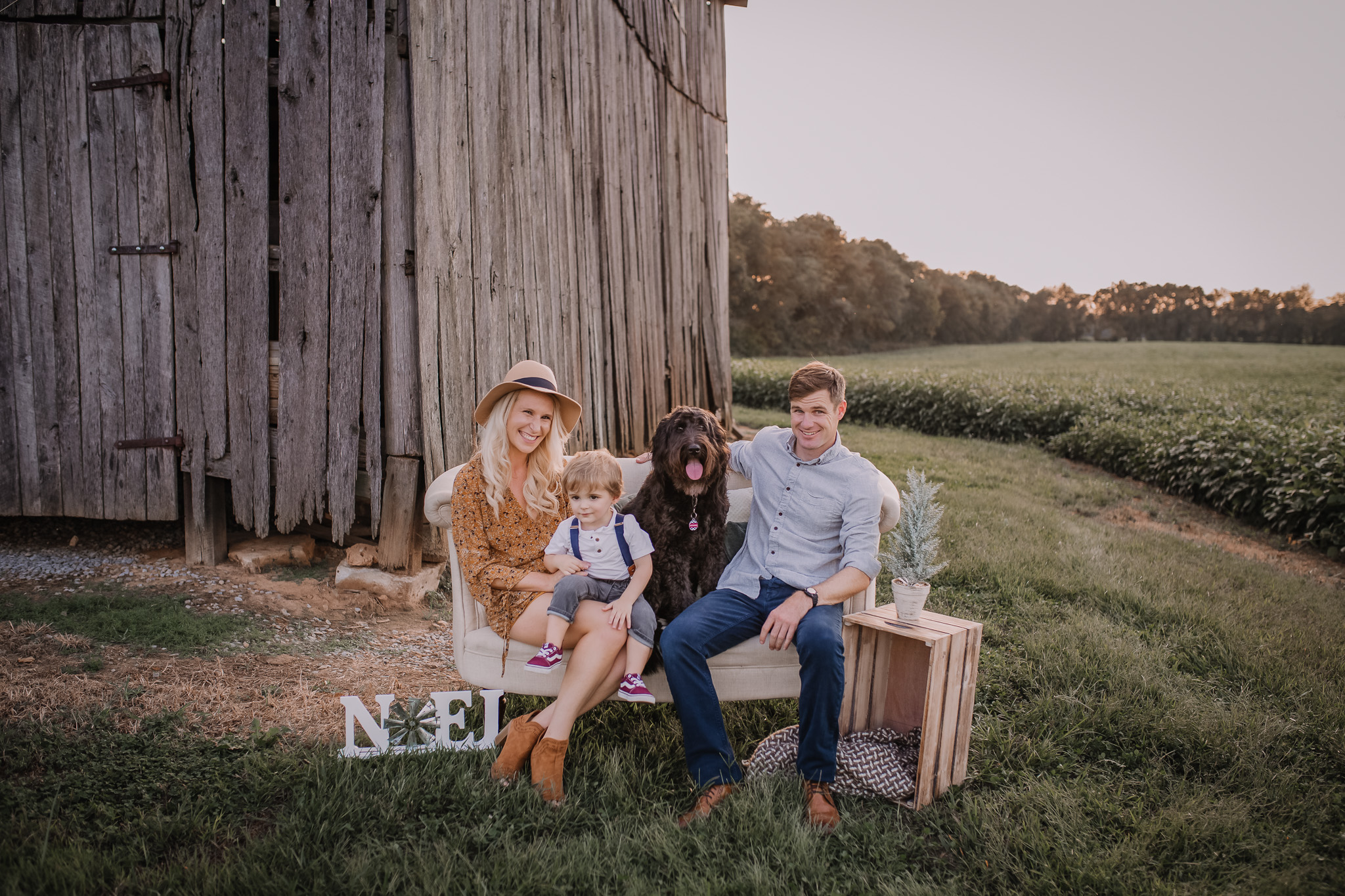 Family sitting on sofa in front of barn with their pup