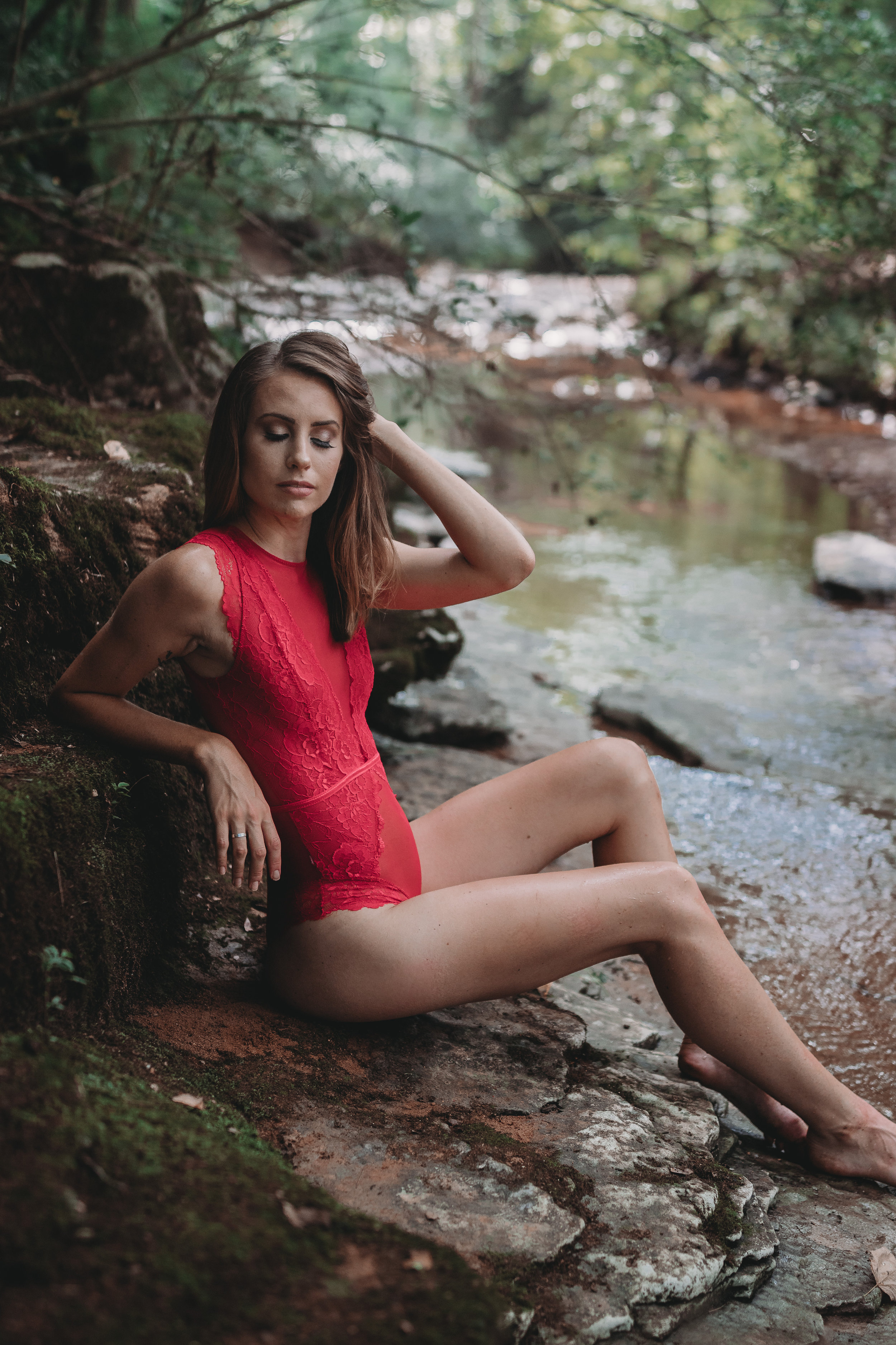 Boudoir girl sitting on rocks by the water