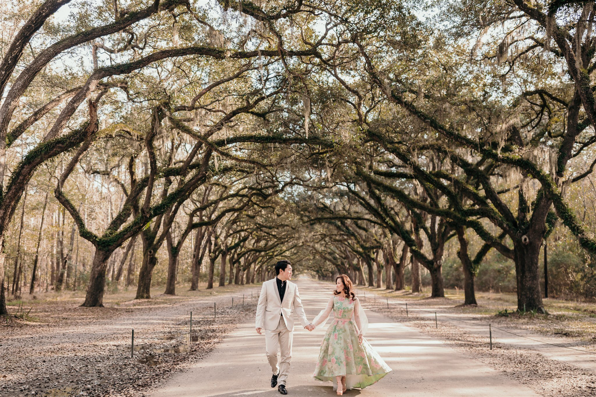 couple walking among moss trees in savannah