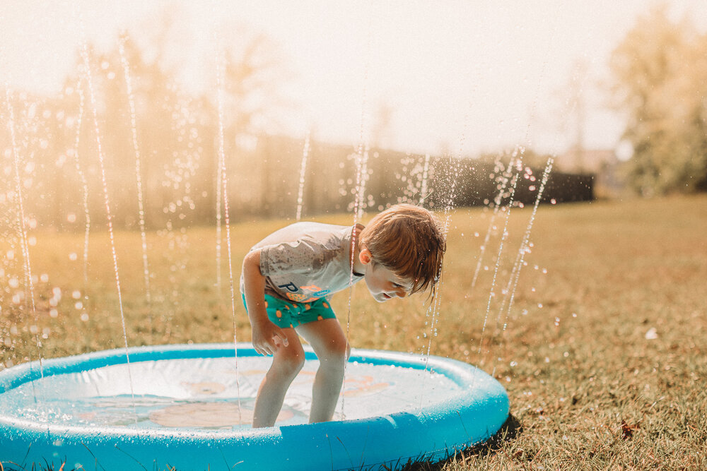 little boy playing in sprinkler outside