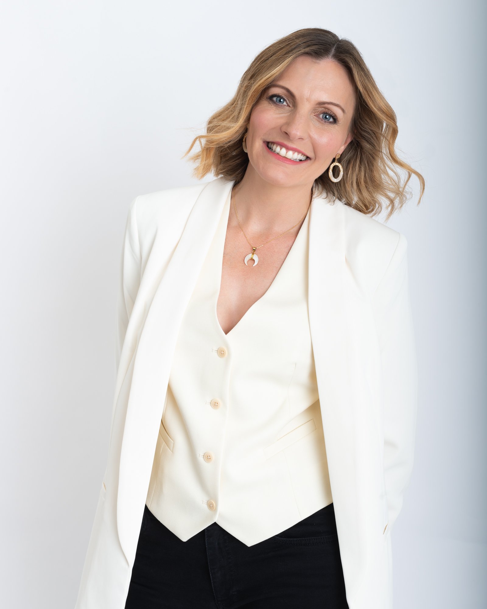 Woman with blonde hair in a white suit smiling at the camera
