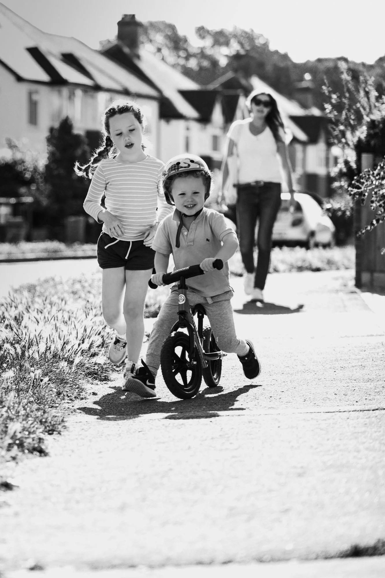 boy on bike with sister running beside and mum behind