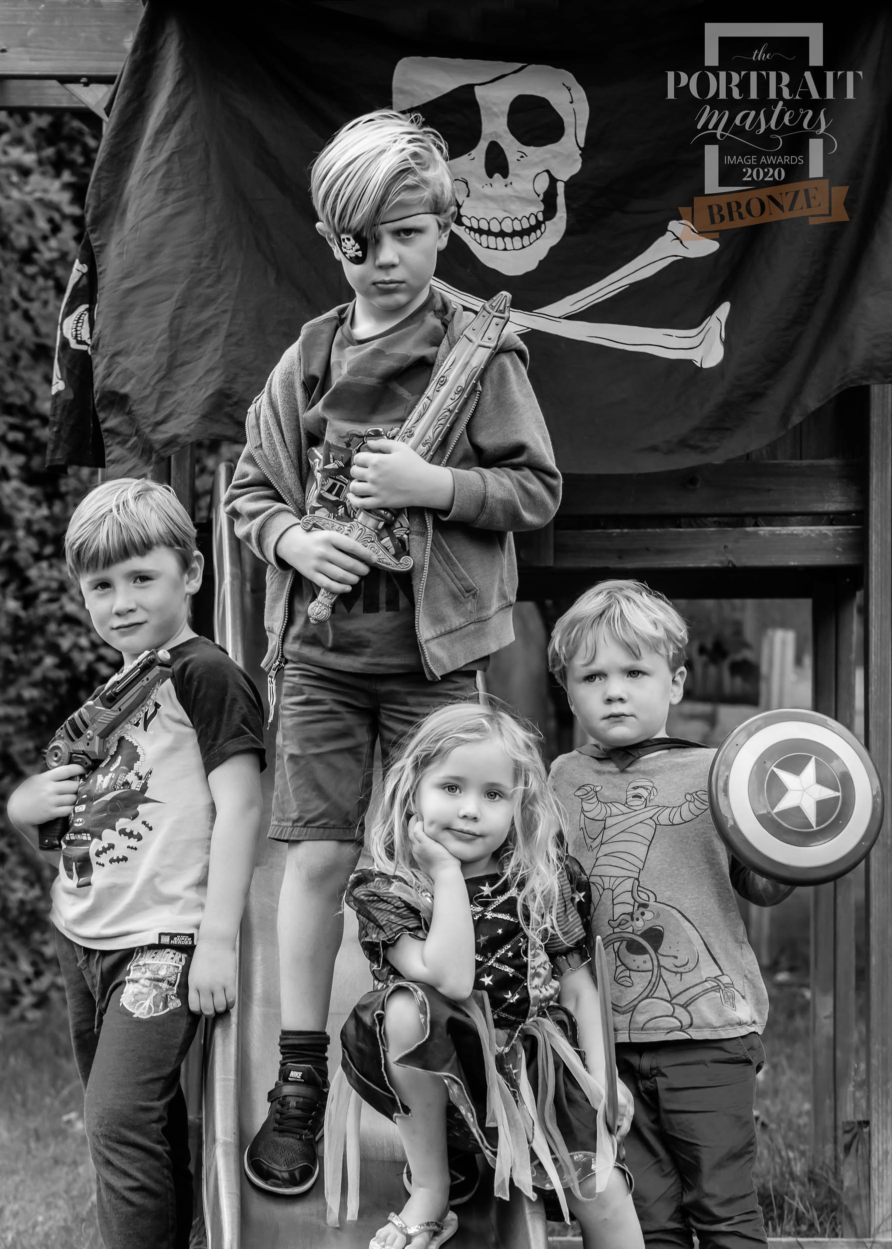 four children dressed up as pirates and superheroes on a climbing frame