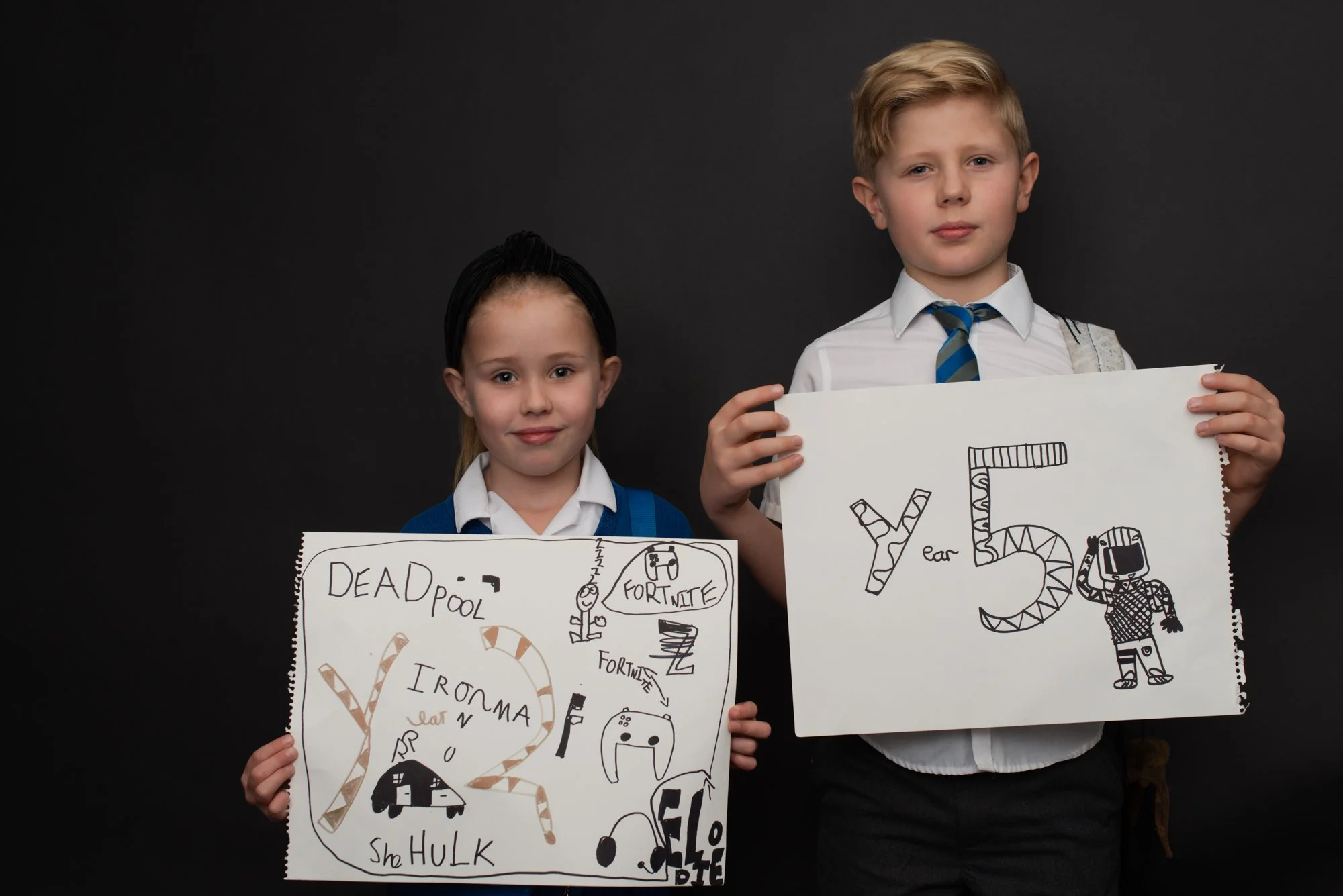 two children in school uniform holding up signs of new year they are entering