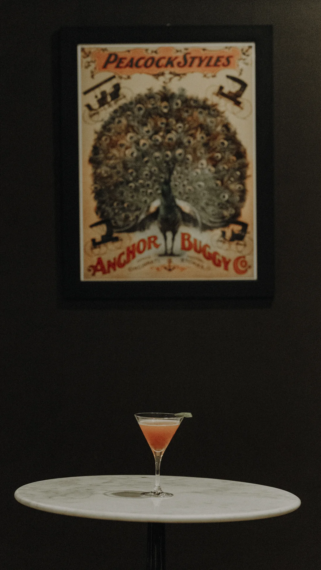 Vivid pink Strawberry Daiquiri cocktail in tall Martini Glass on marble counter with peacock painting in background at Americano Coffee Lounge 434 Houston Street Suite 120 Nashville Tennessee 37203