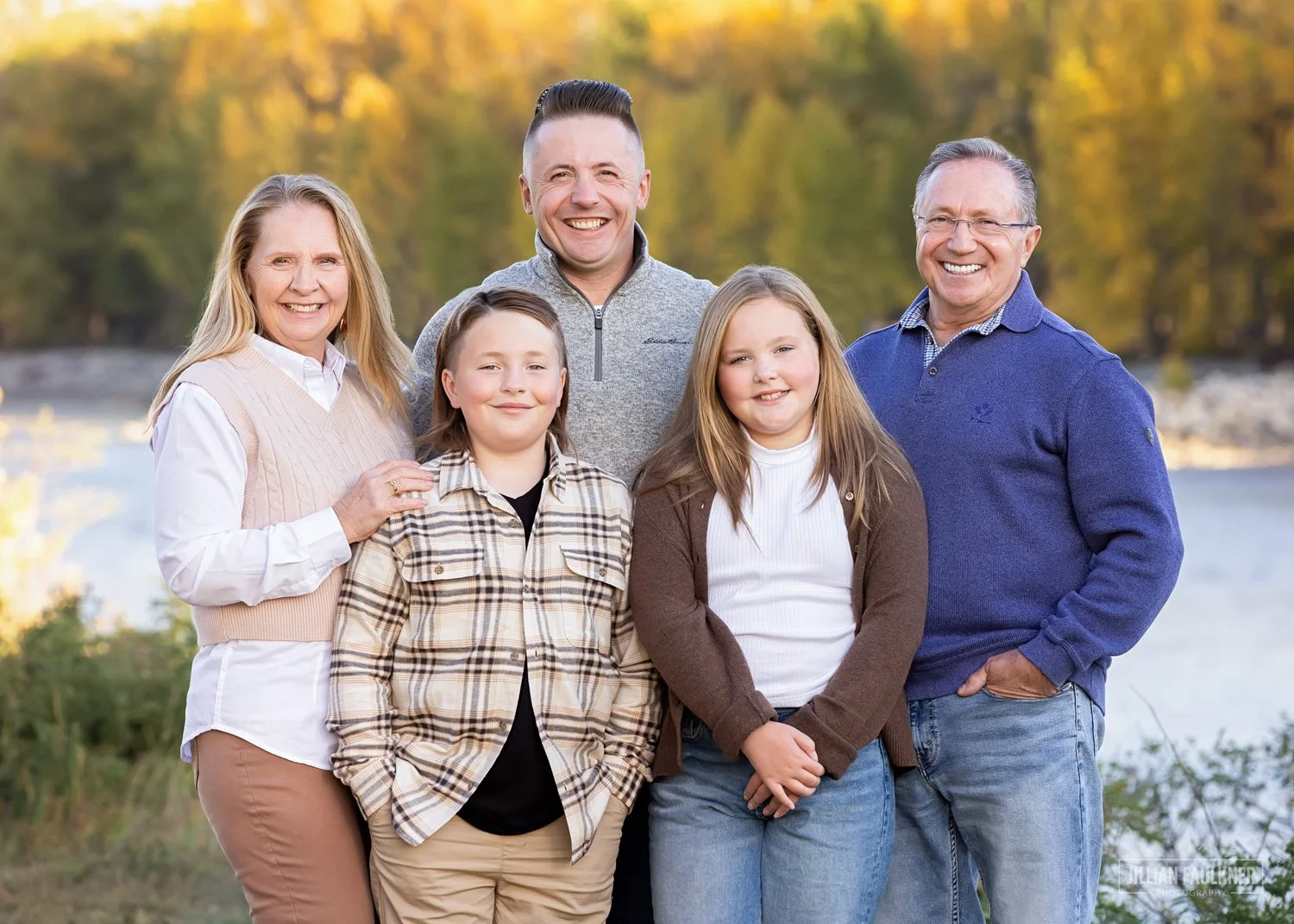 grandparents with grandchildren and son photographed at Baker Park with the Bow River in the background