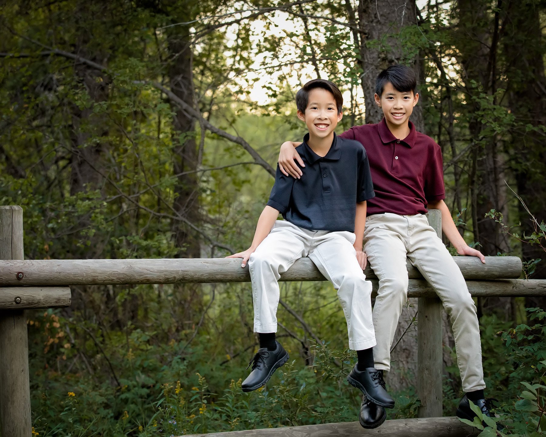 outdoor child portrait photography of two boys on fence at Griffith Woods Park in Calgary
