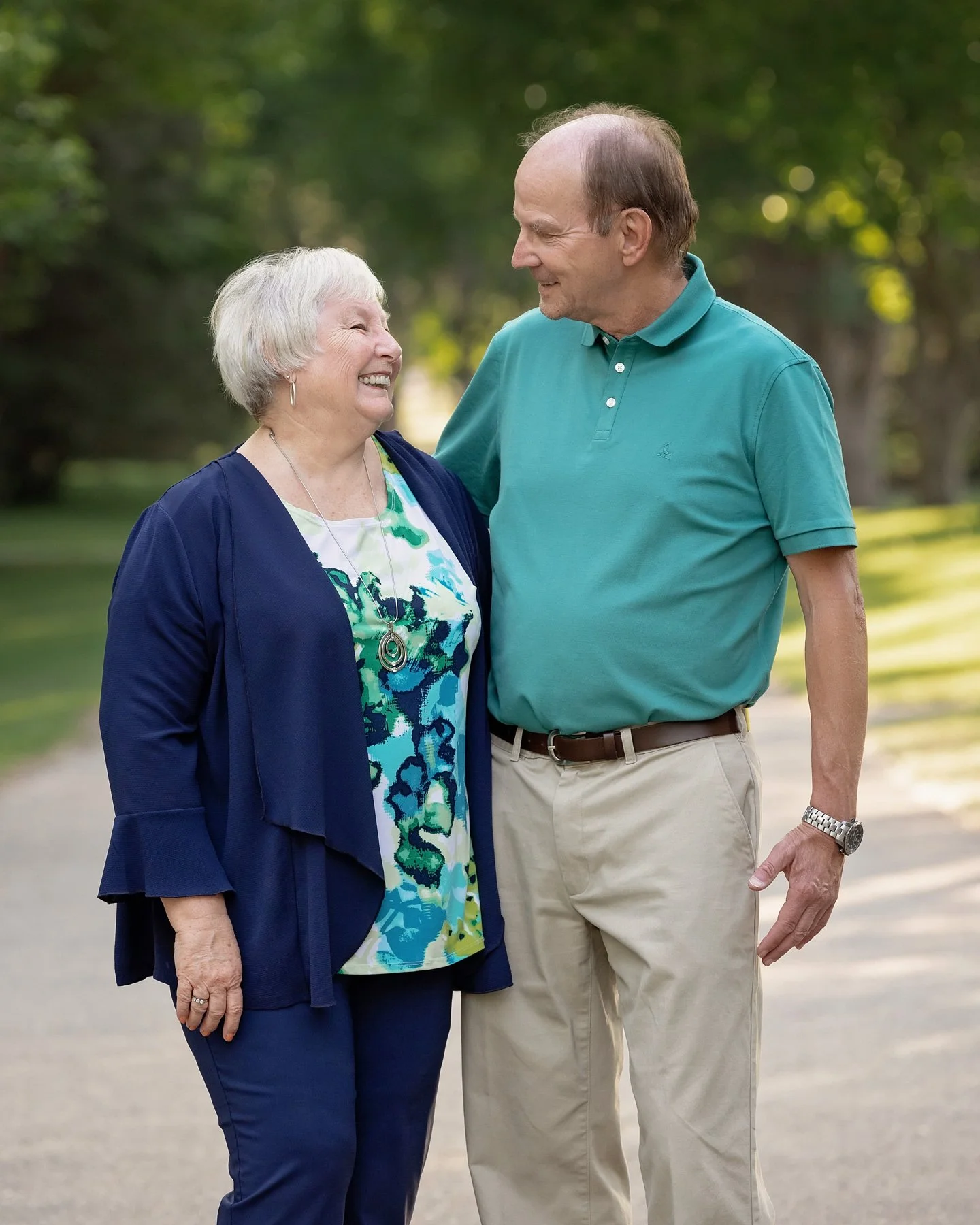 candid portrait of senior couple under neath a pathway of trees at Baker Park in Calgary