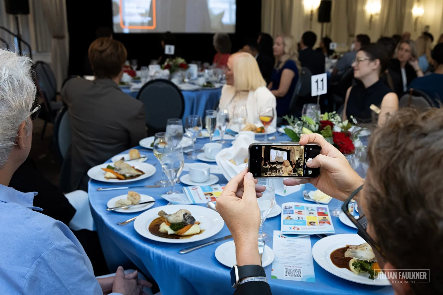 Calgary event photographer capturing guest taking a video of emotional moment at VIP gala