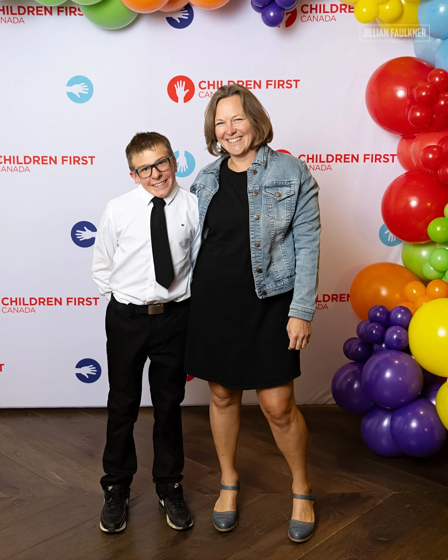 Corporate guests networking and posing at Children First Canada branded photo wall Calgary