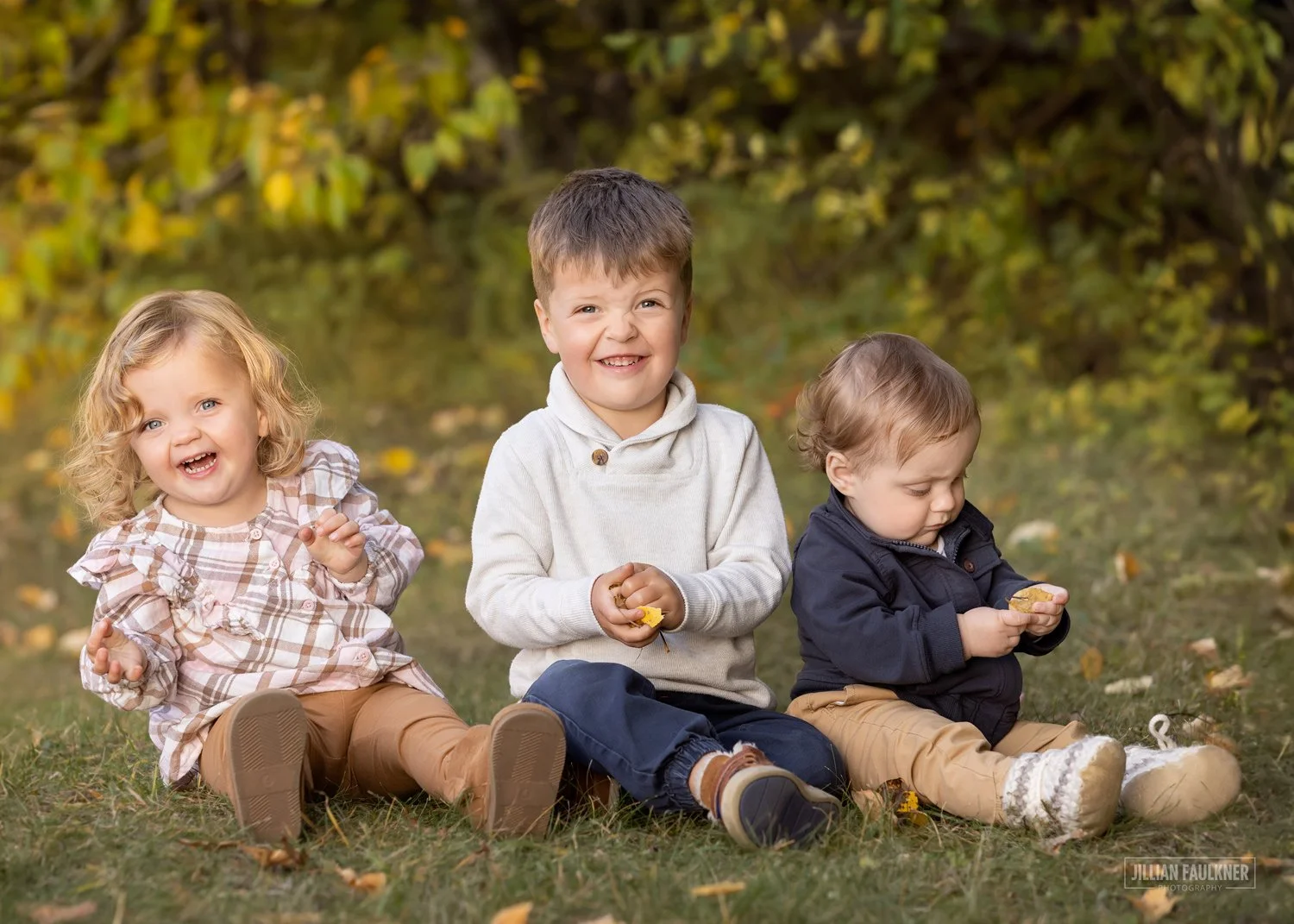 children’s outdoor portrait playing in fall leaves at Baker park in Calgary