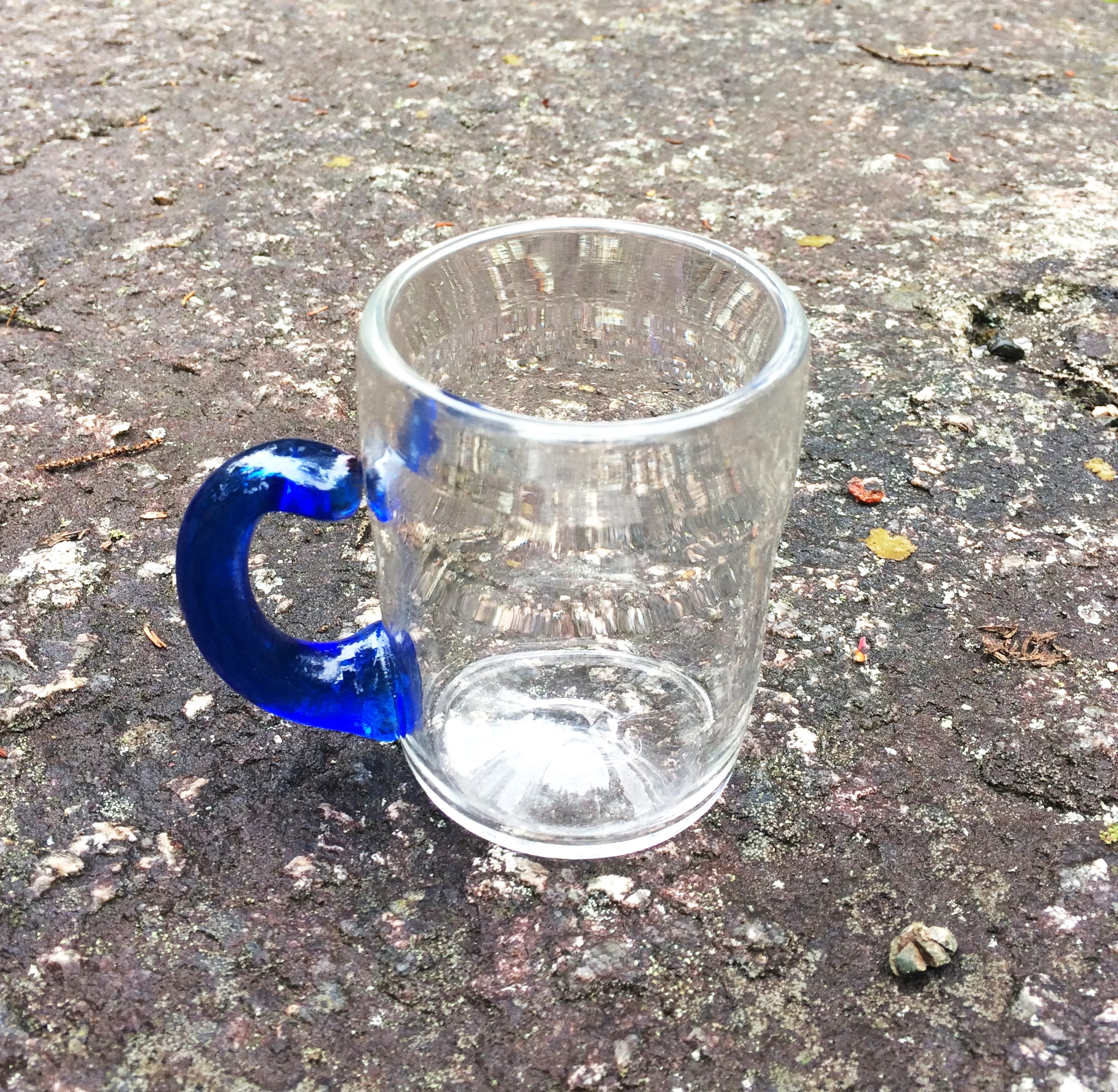 Small mug with blue handle sits perched on a boulder left by a glacial erratic.