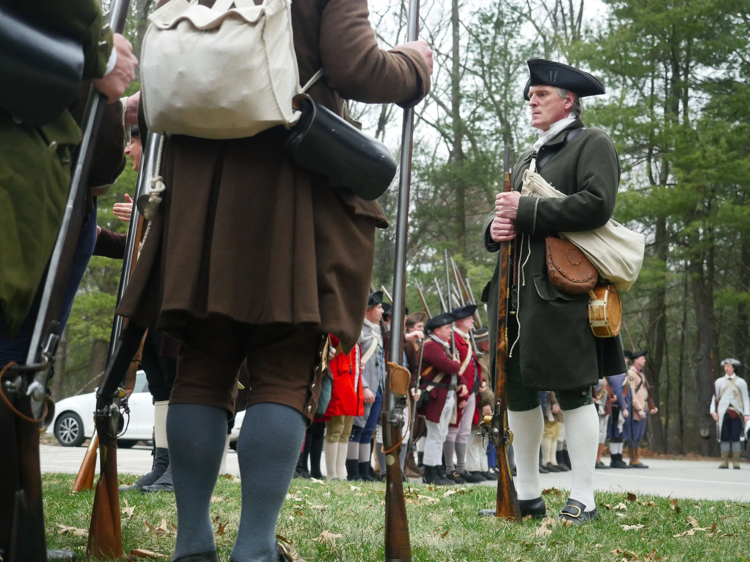 Lincoln, MA - April 14th, 2018 - Hannes Klein looks onto the fourth battalion members prior to walking to the battle ground. All guns used in the reenactments are direct replicas of what the militia would have used. “You can still buy the replicas, they’re readily available … They go anywhere from $600 to $1200 dollars.”
