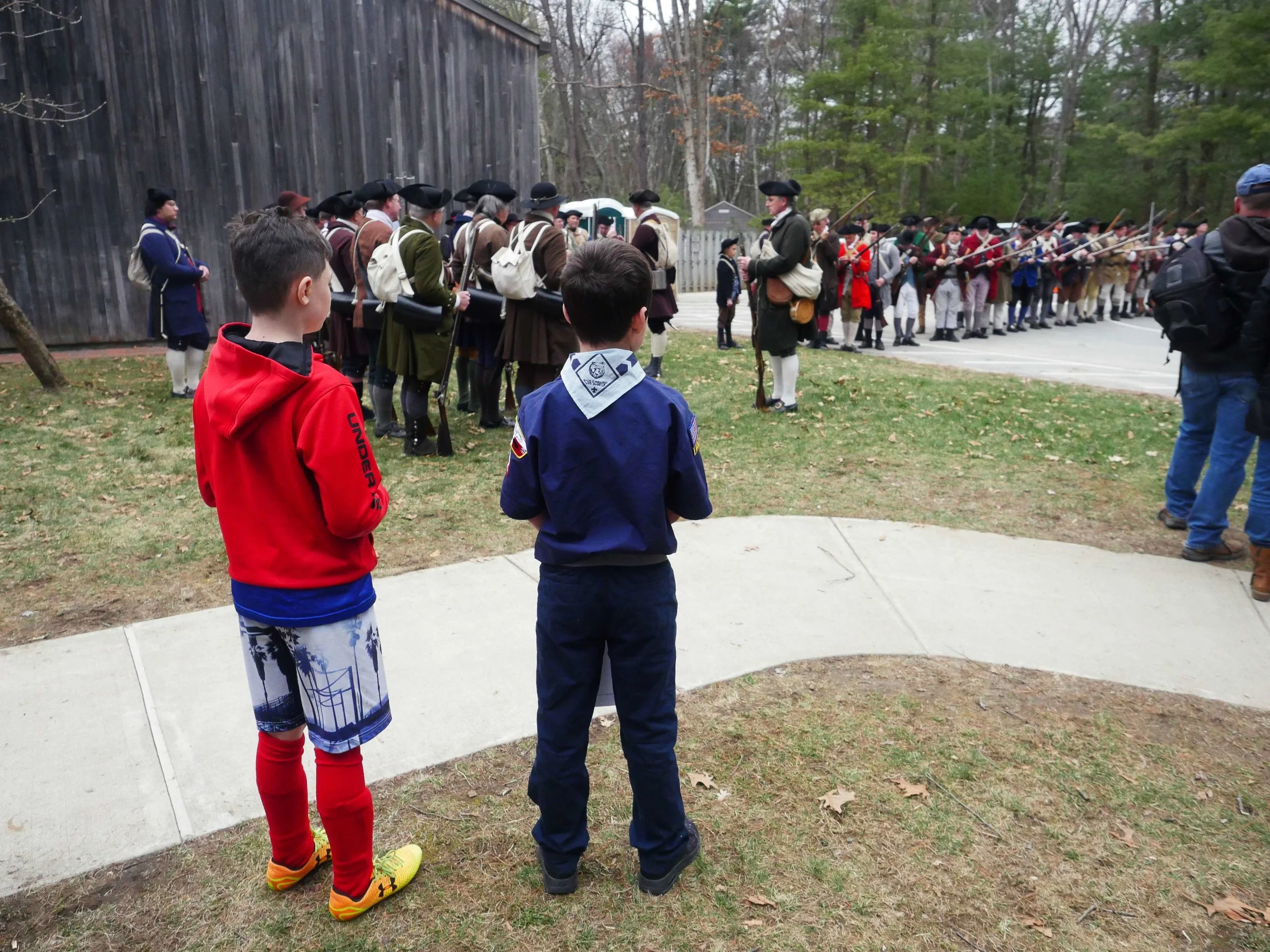 Lincoln, MA - April 14th, 2018 - Two young boy scouts look on as Hannes Klein rallies the troops for the 243rd anniversary of the Battles of Lexington and Concord. Klein says that the battle still garners a large crowd even in the inclement of weather.