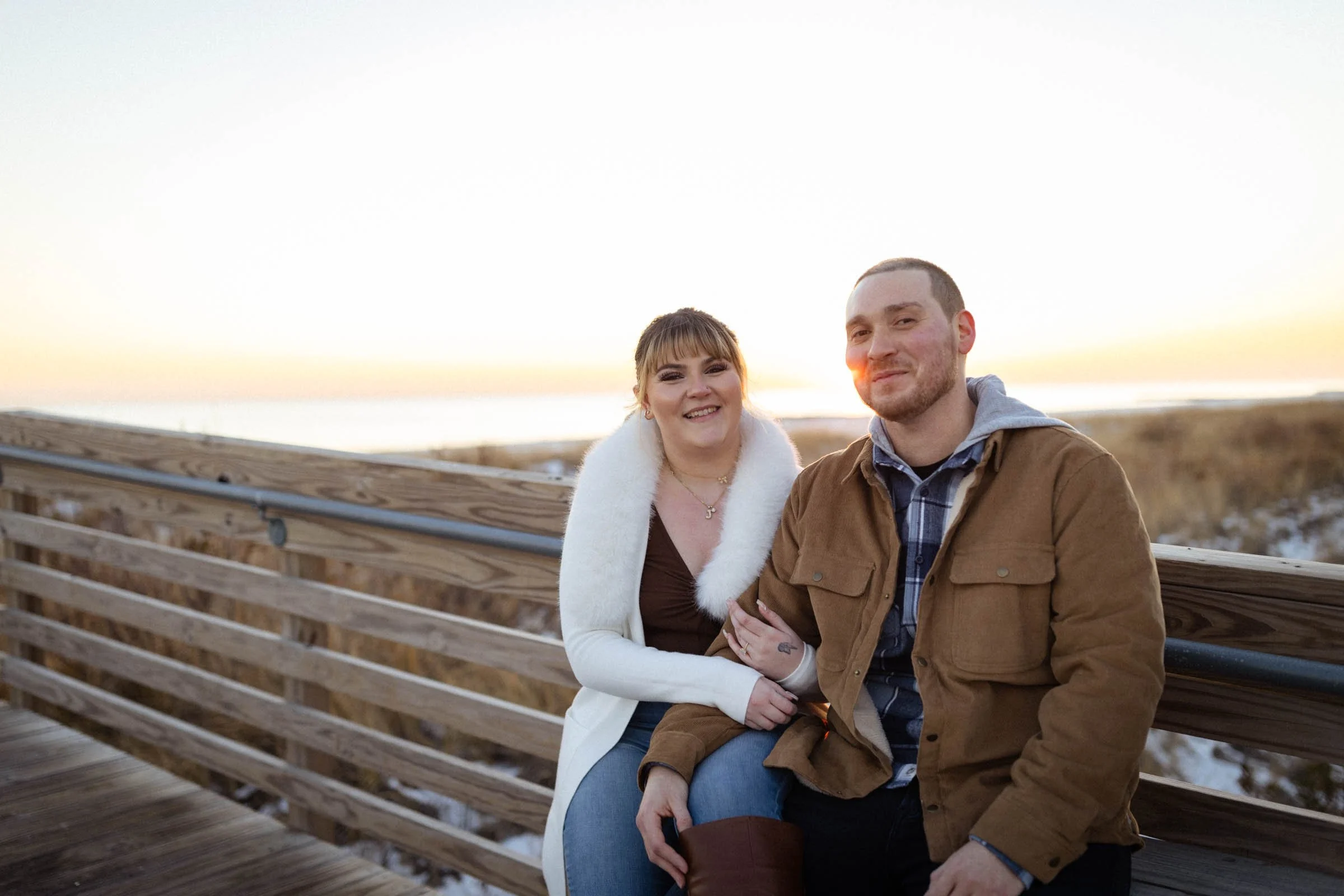  couple smiling and sitting on bridge at sunset 